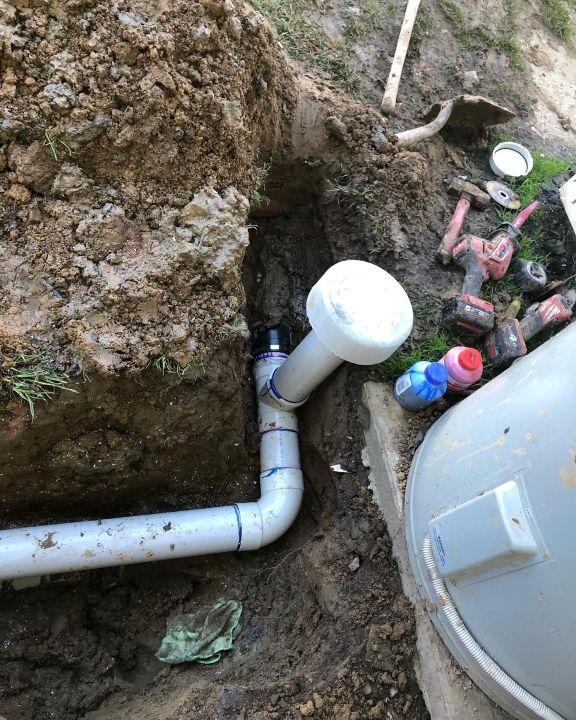 A Pipe is Being Installed in the Ground Next to a Water Heater — T. Woods Plumbing in Bathurst, NSW
