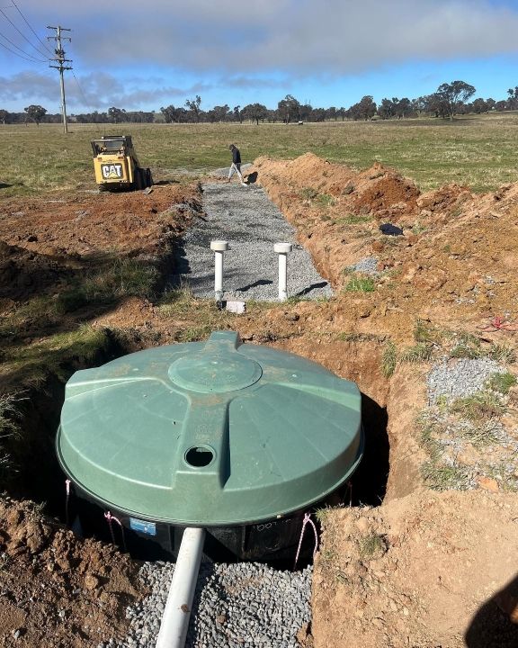 A Green Tank is Sitting in the Middle of a Dirt Field — T. Woods Plumbing in Bathurst, NSW