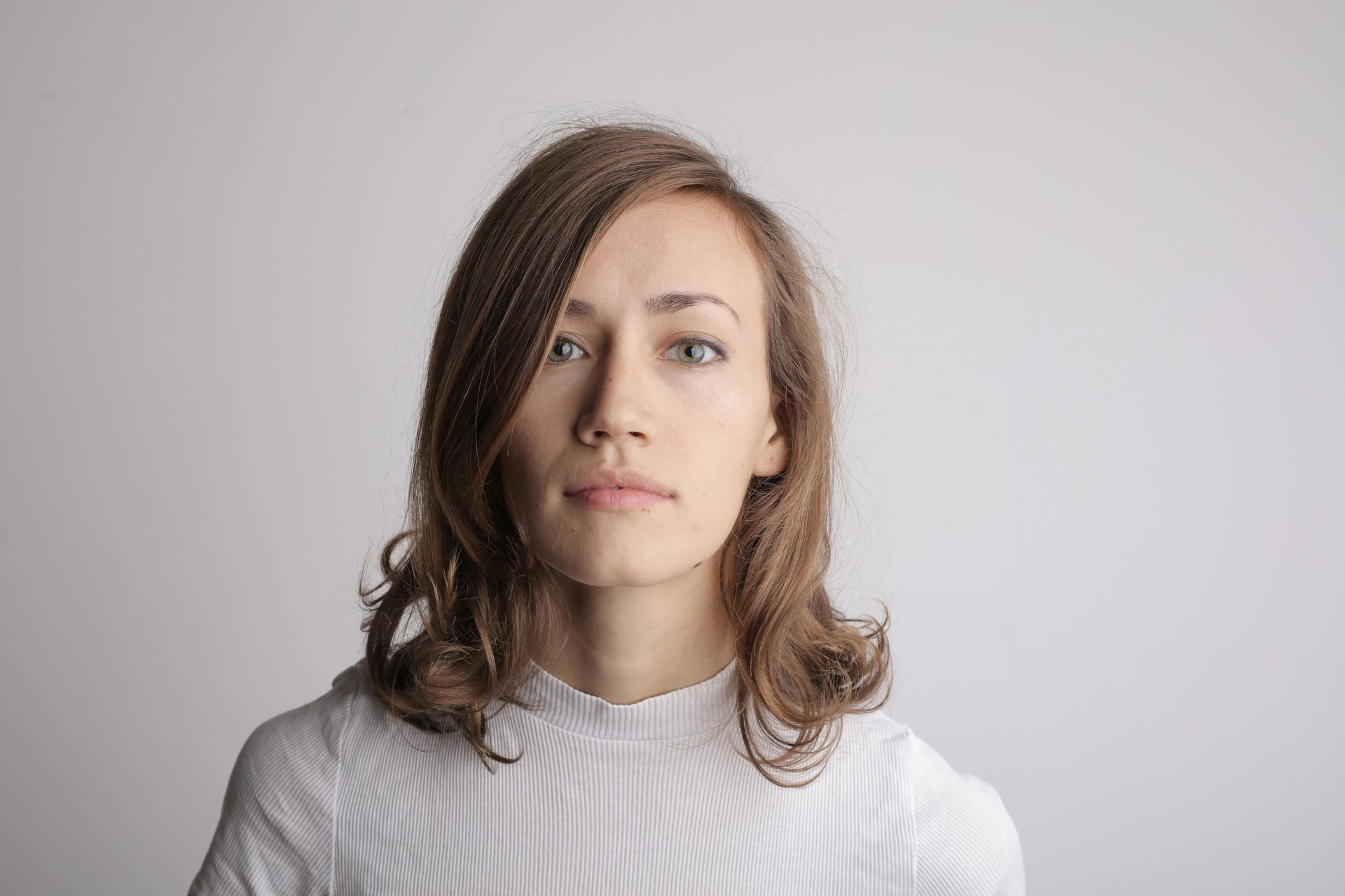 Woman with light brown hair, wearing a white sweater, looking forward with a neutral expression.