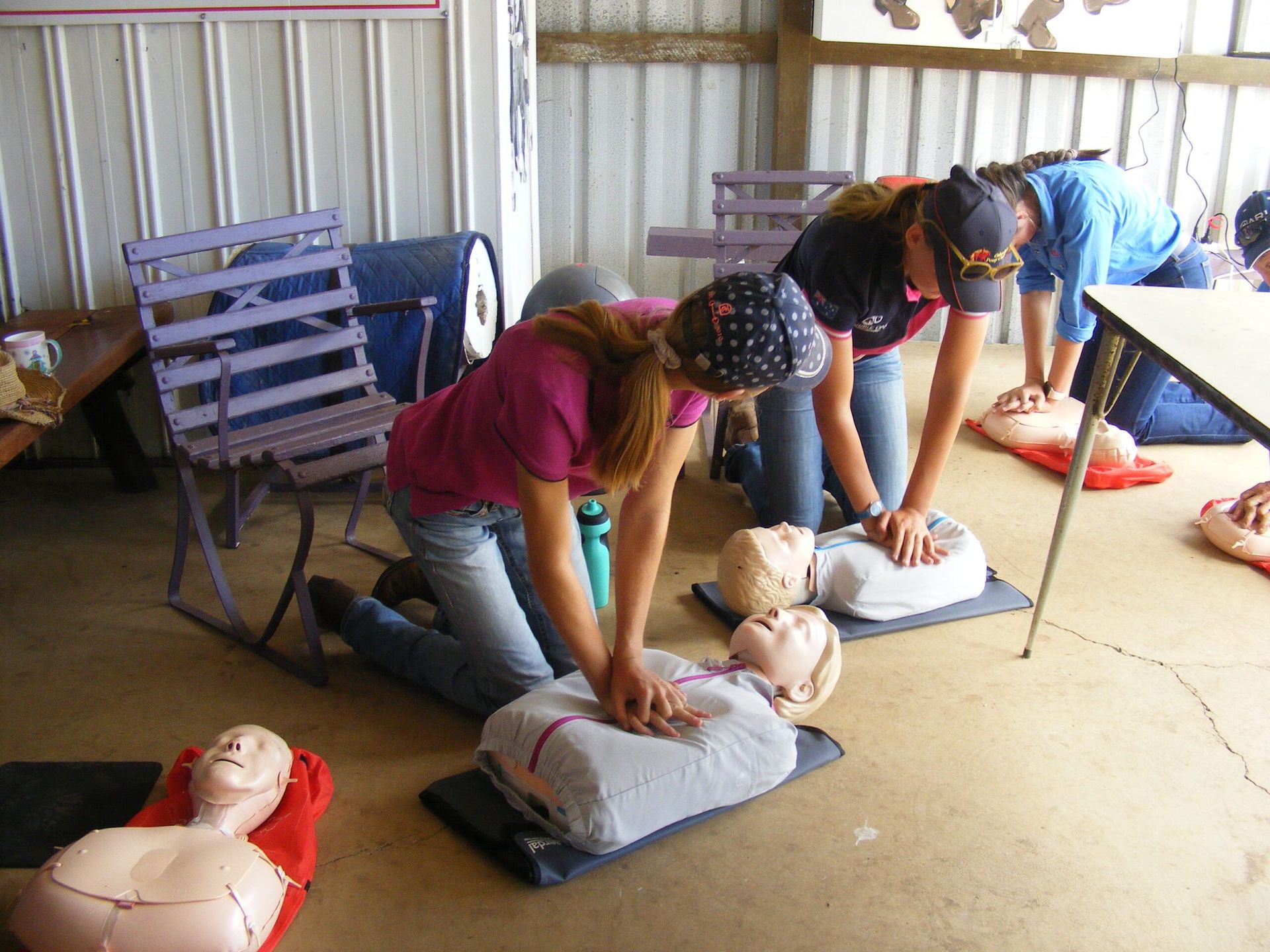 People practicing CPR on mannequins during a training session. Indoor, various angles, light setting.