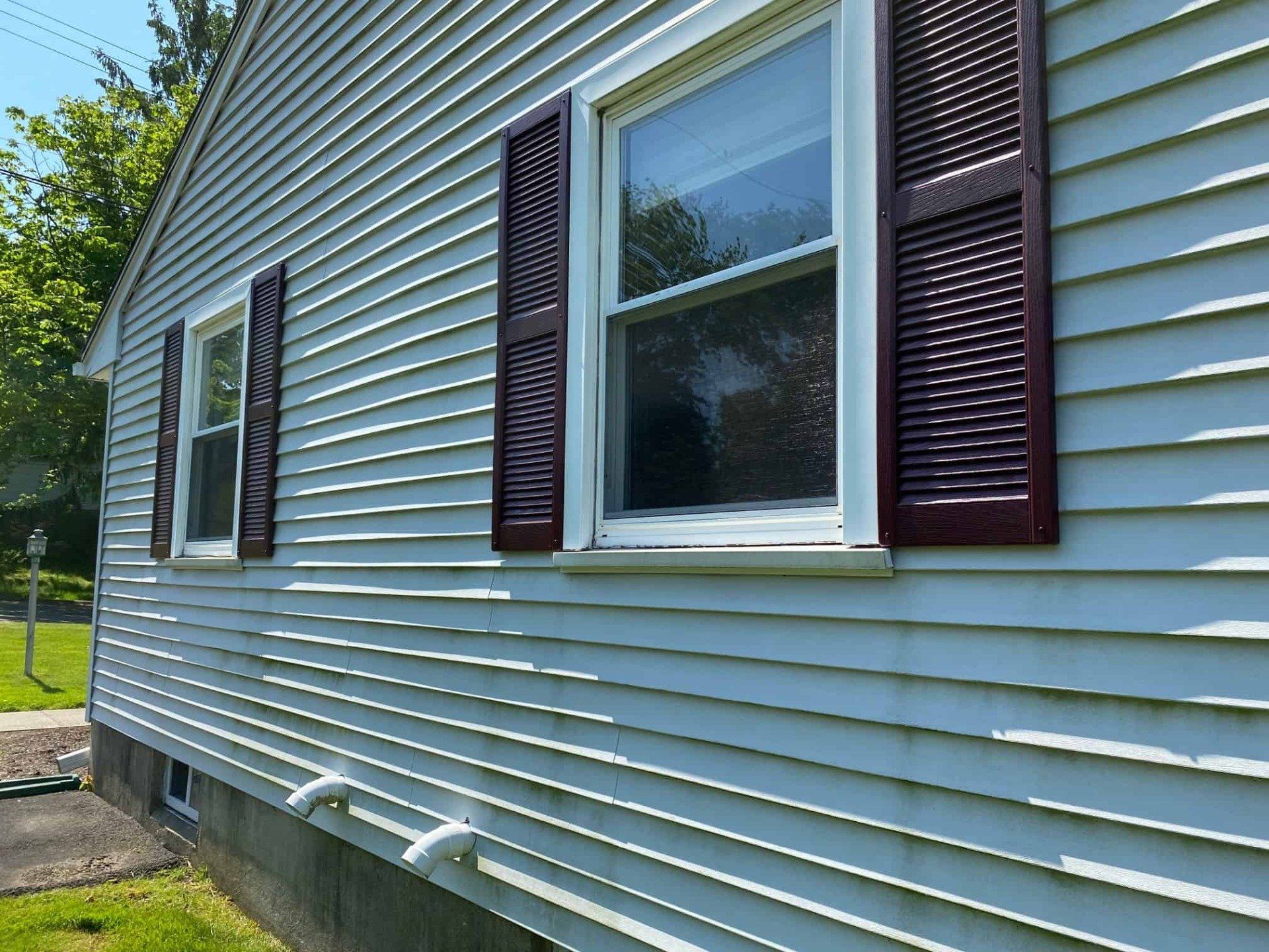 A white house with red shutters on the windows.