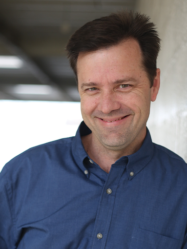A man in a suit and white shirt is smiling for the camera.