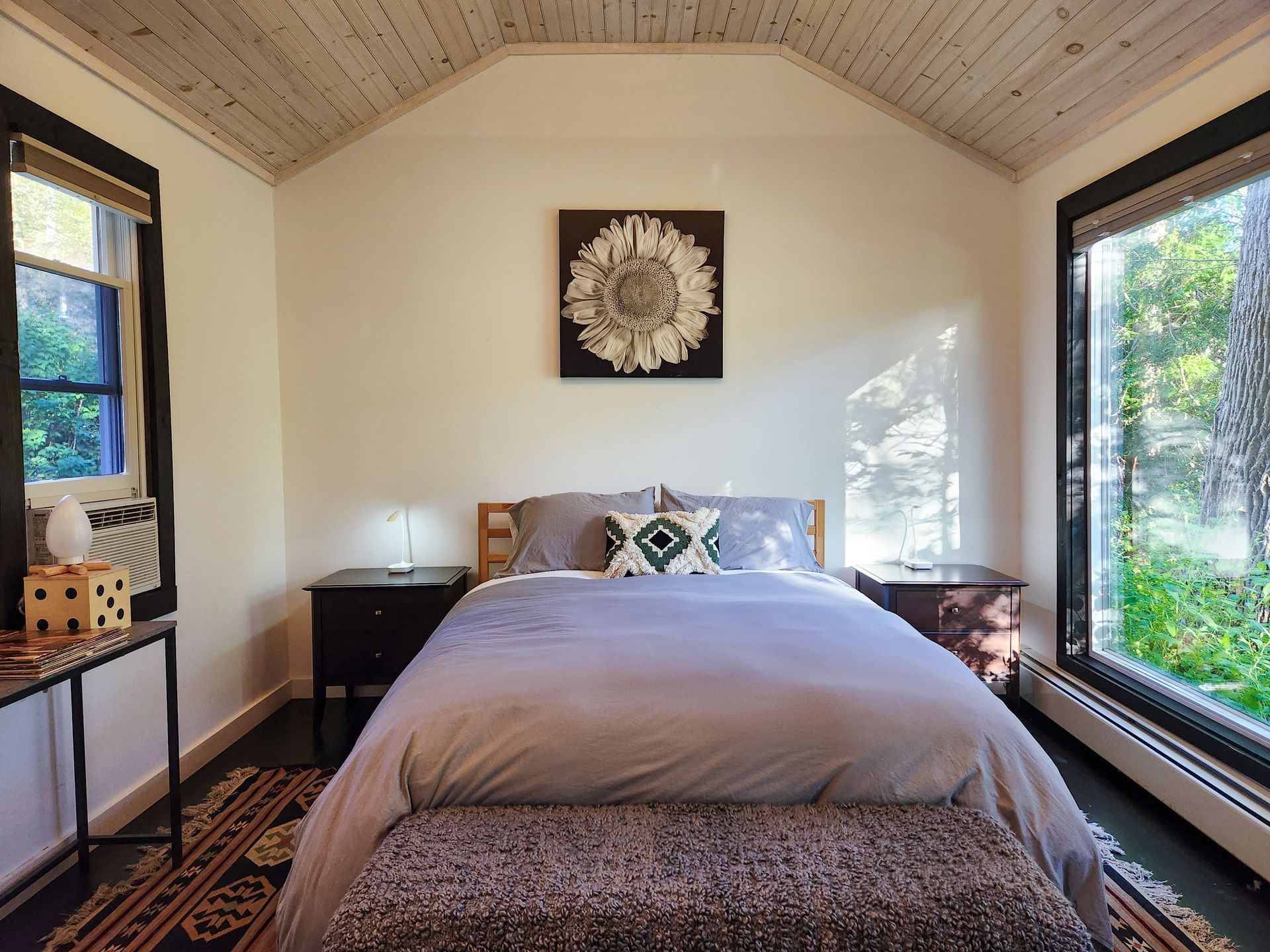 Cozy interior of a Belleayre Lodge Cabin, showing bed, decor on walls, and beautiful views of Catskills outside window.