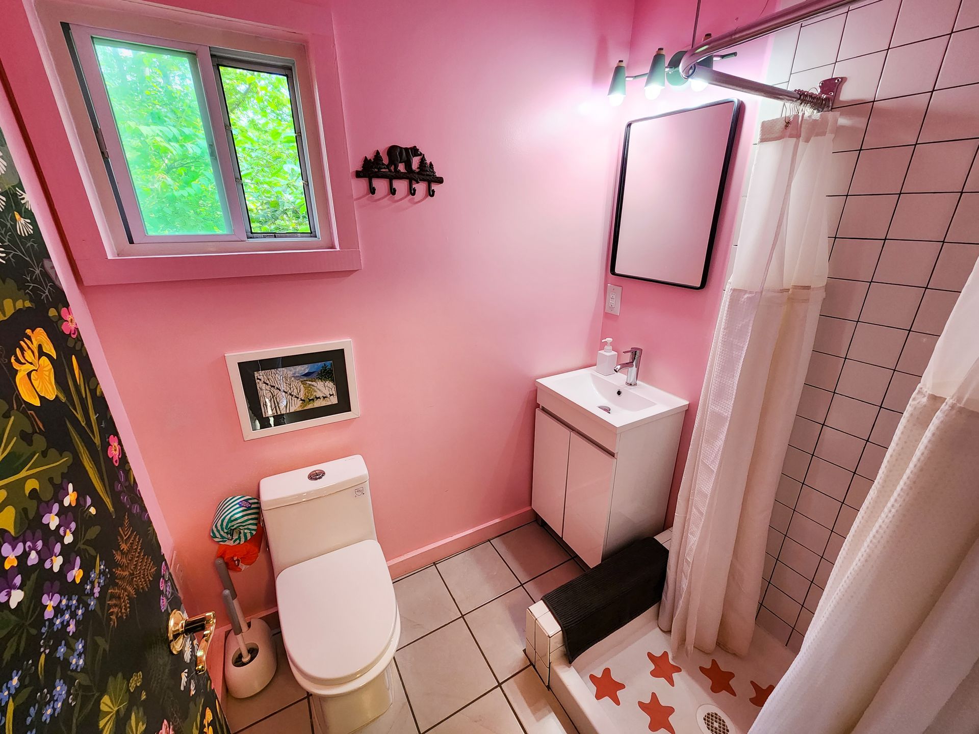 Bathroom of Cabin #2 at Belleayre Lodge; beautiful Catskills views, pink walls, toilet, sink, mirror, and standing shower.