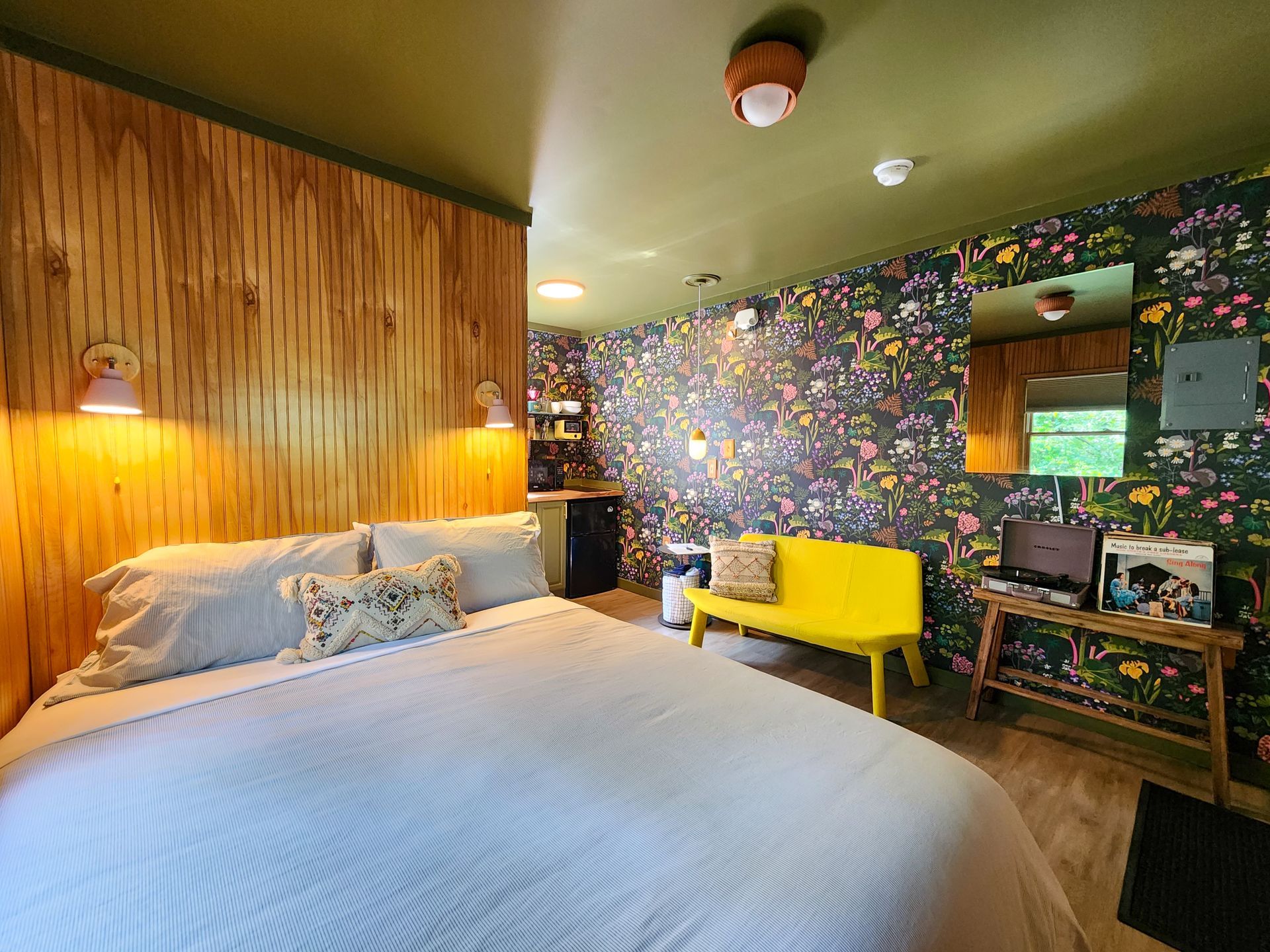 Cozy interior of a Belleayre Lodge hotel-style cabin, showing bed, beautiful Catskills views out the window, and sofa.