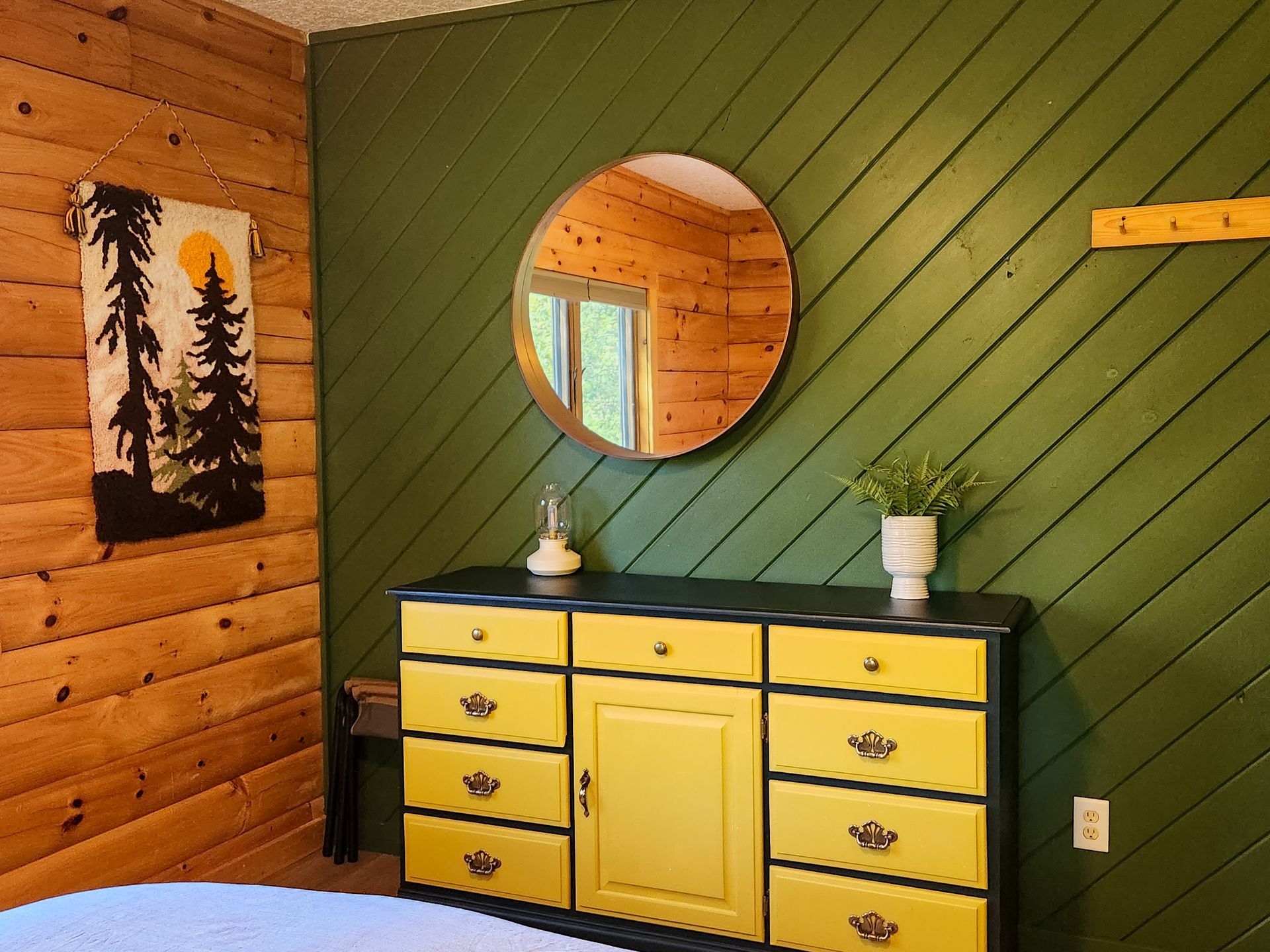Wall of Cabin #4's cozy bedroom area at Belleayre Lodge, showing lovely dresser and circular mirror.