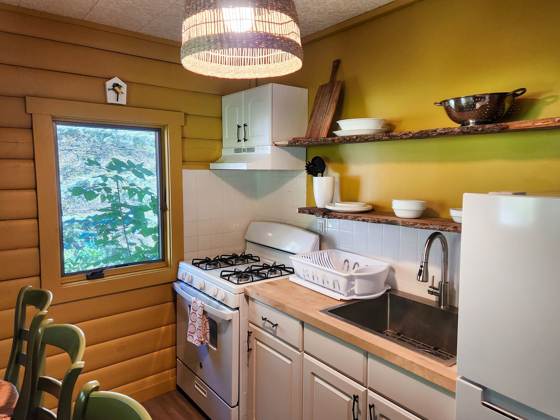 Cozy kitchenette of Cabin 4A at Belleayre Lodge, showing cabinets, stoves, refrigerator, and barstools at a counter.