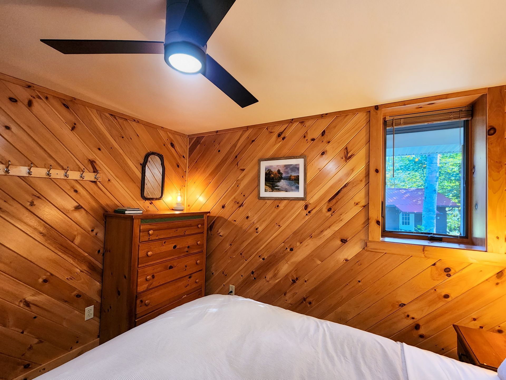 Cozy bedroom of Cabin #4B at Belleayre Lodge, showing bed, dresser, stylish wall decor.
