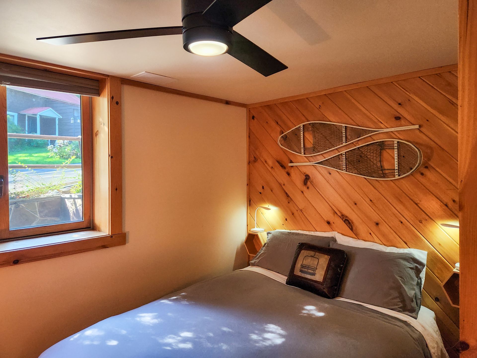 Cozy bedroom of Cabin #4B, showing bed, outdoor views, stylish wall decor.