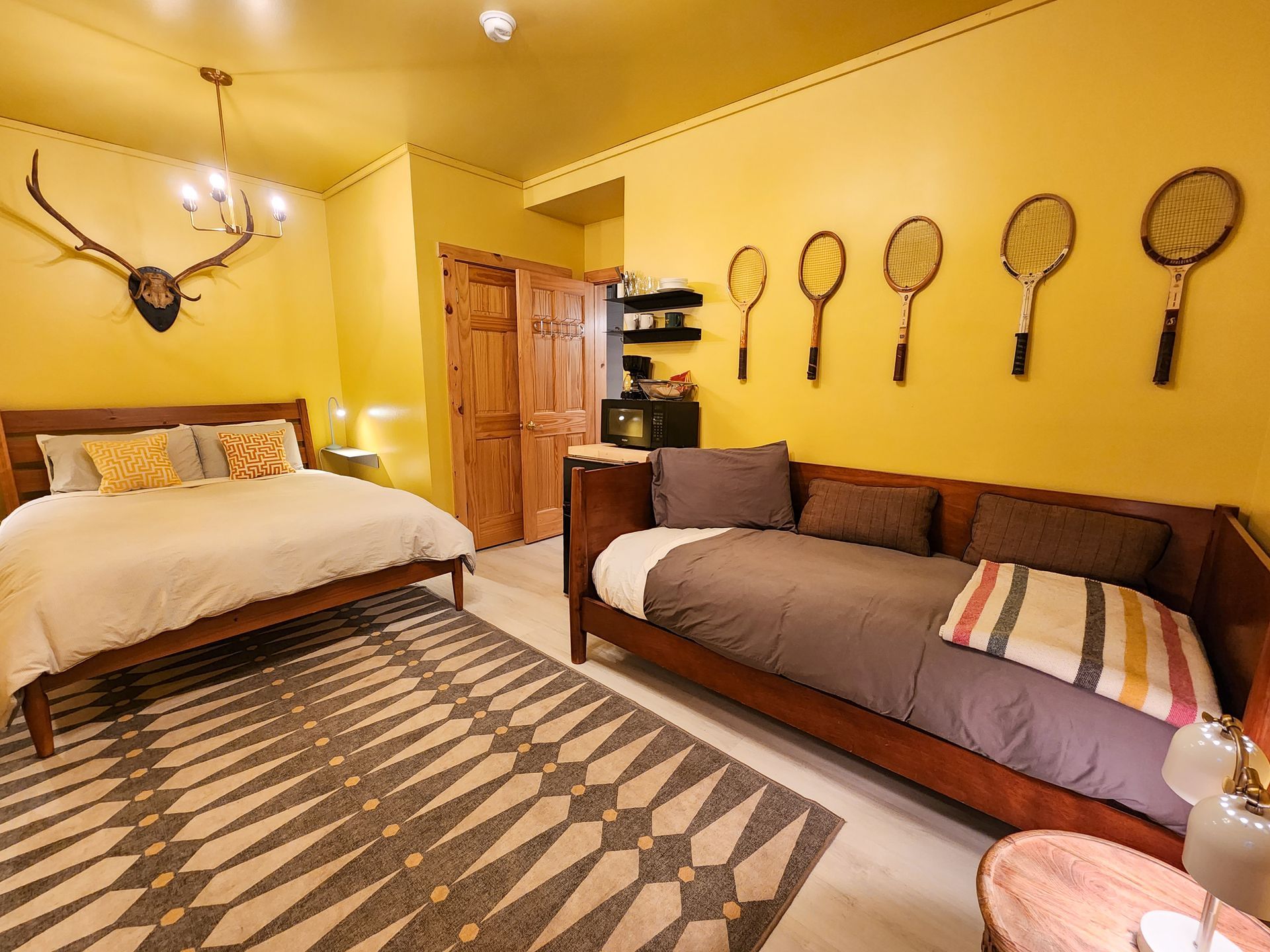 Cozy hotel-style bedroom of Cabin #7, showing queen bed, day bed, stylish wall decor, and ceiling lights.