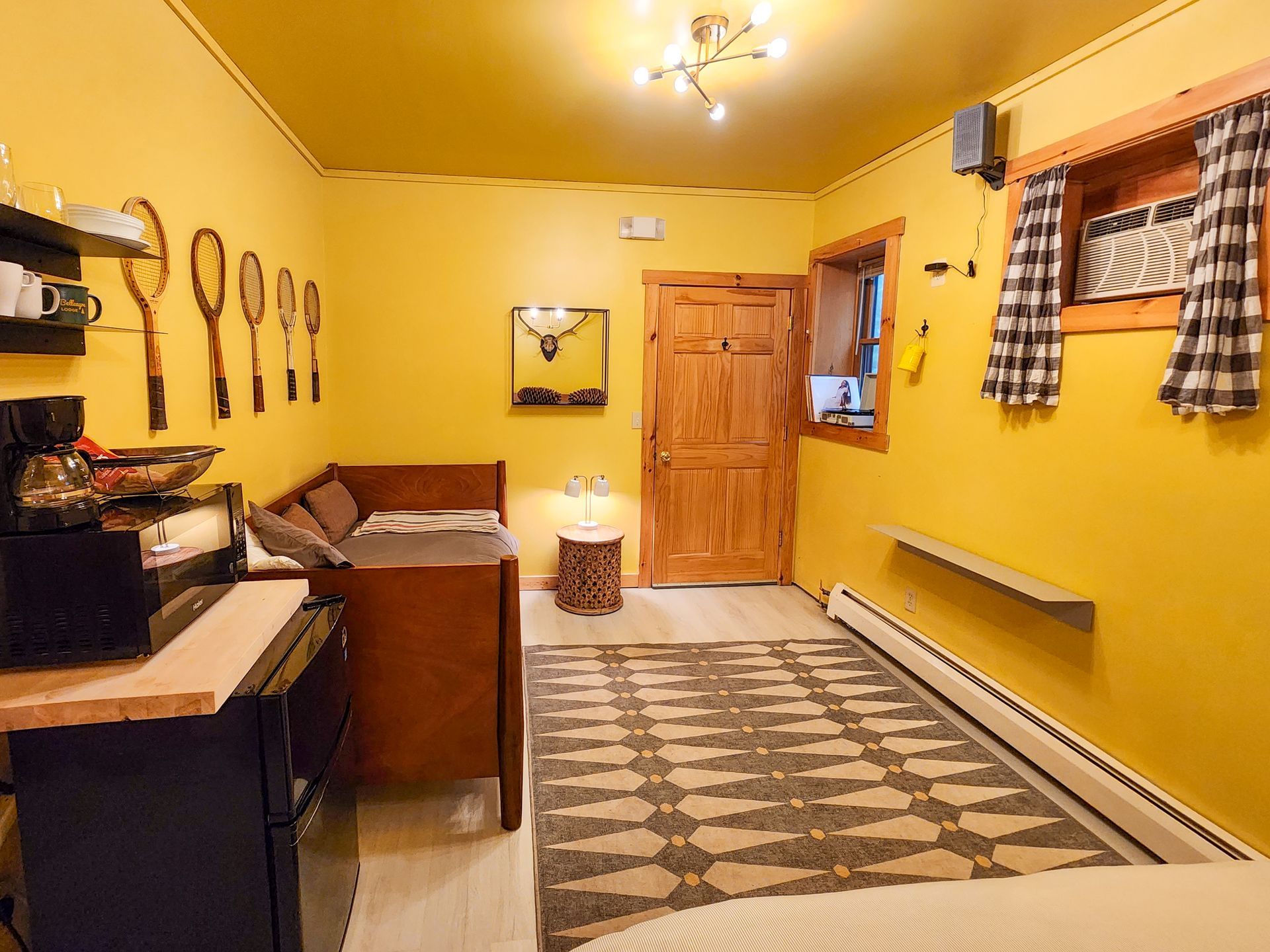 Cozy hotel-style bedroom of Cabin #7, showing queen bed, day bed, stylish wall decor, and ceiling lights.