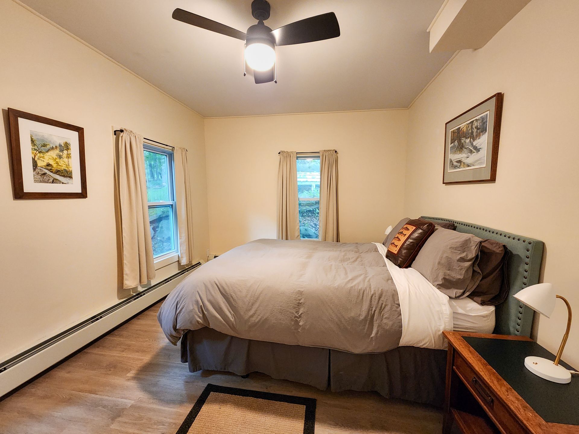 Cozy bedroom of Cabin #9 at Belleayre Lodge, showing queen bed, decorative art, and bedside lamps.
