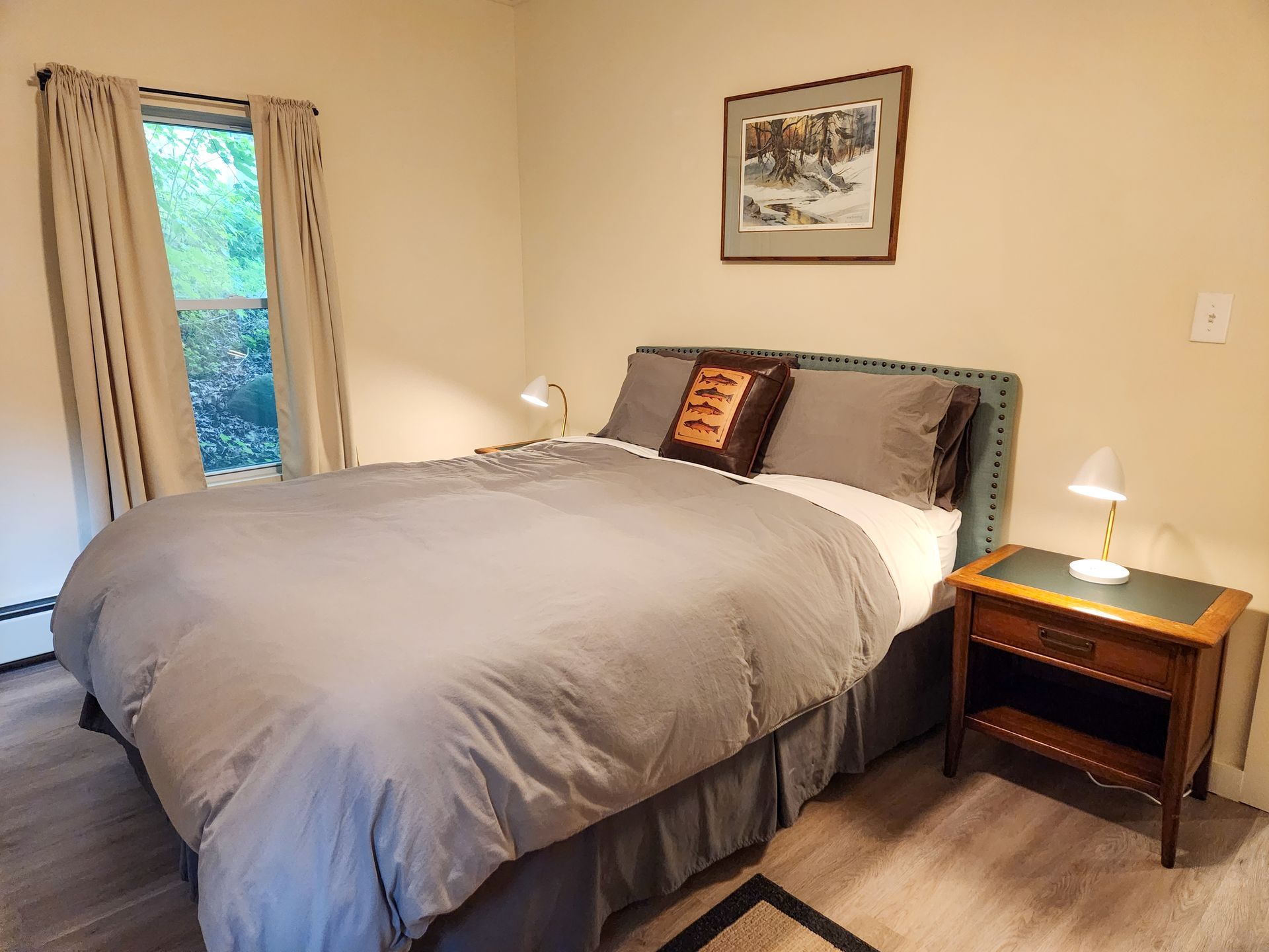 Cozy bedroom of Cabin #9 at Belleayre Lodge, showing queen bed, decorative art, and bedside lamps.
