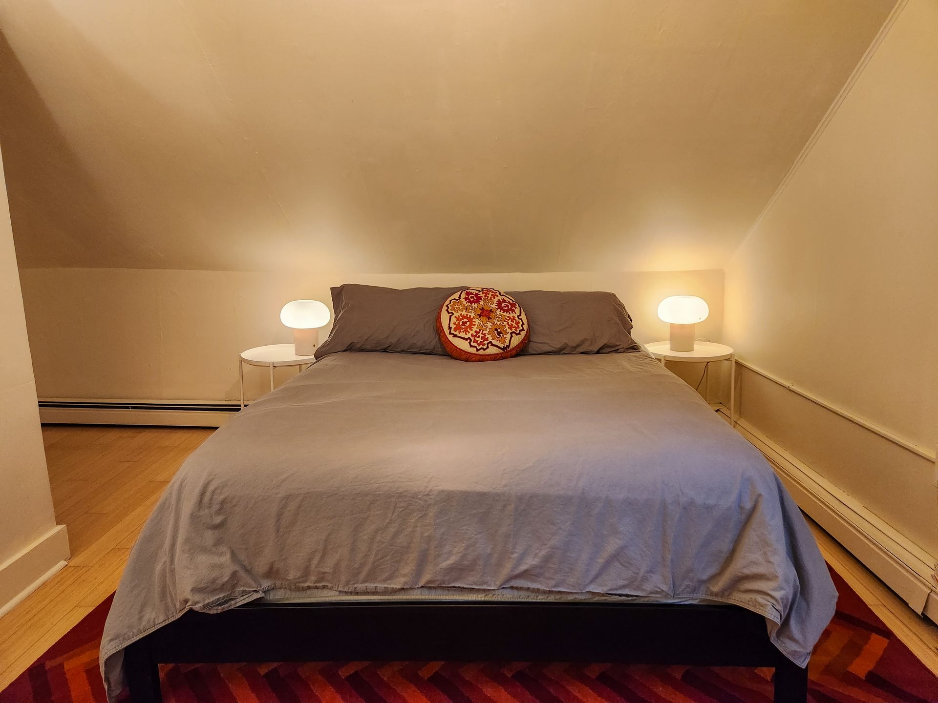 Cozy bedroom of Cabin #9 at Belleayre Lodge, showing queen bed, decorative art, and bedside lamps.