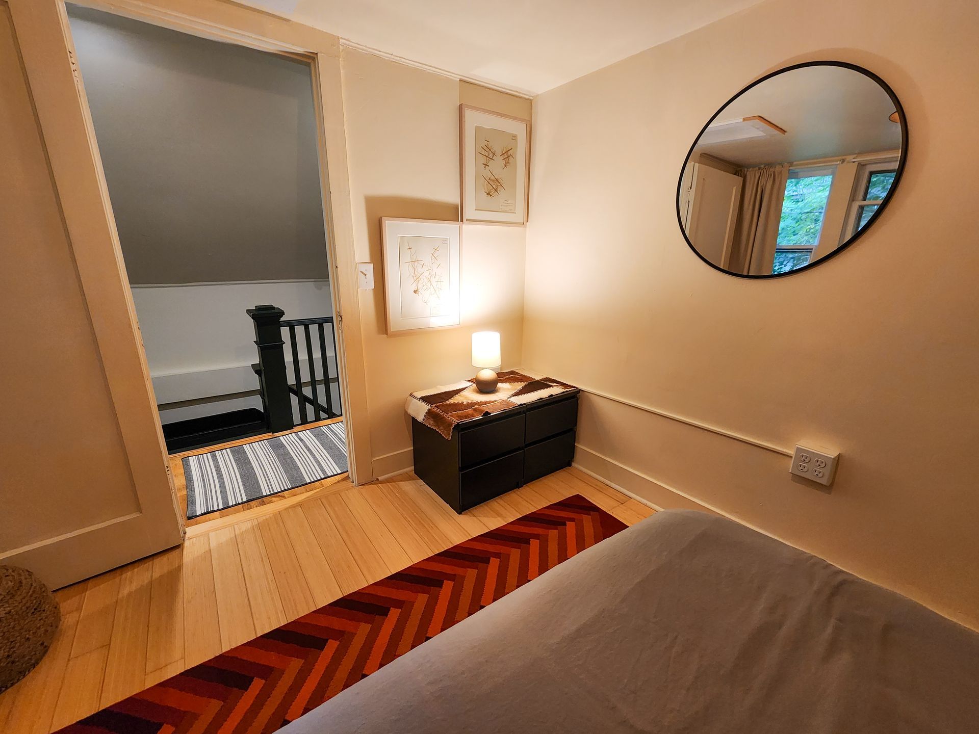 Cozy bedroom of Cabin #9 at Belleayre Lodge, showing queen bed, decorative art, and bedside lamps.