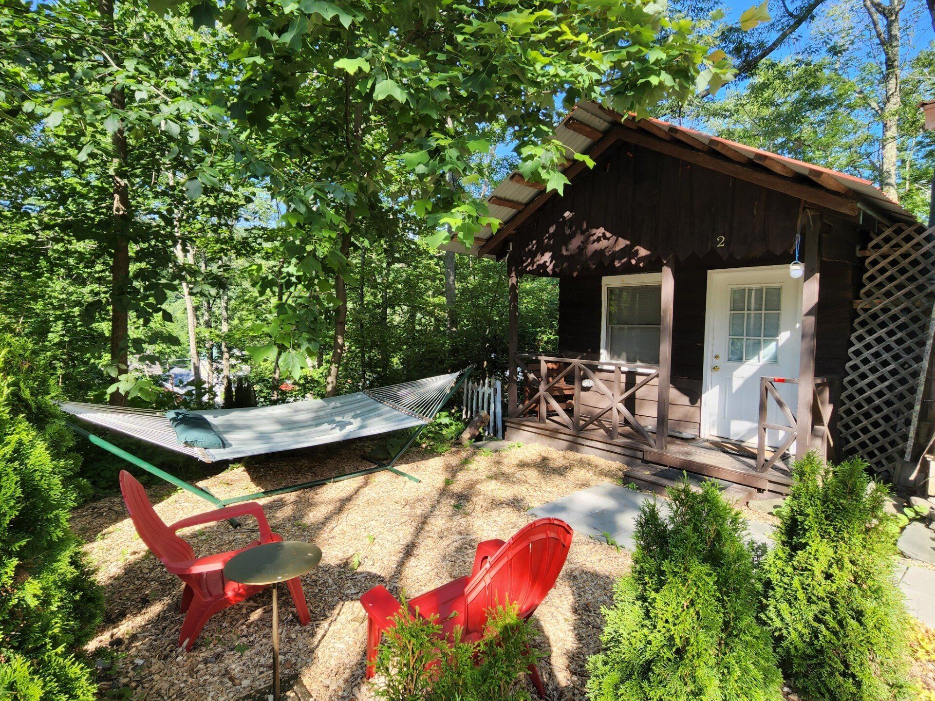 Exterior of Cabin #2 at Belleayre Lodge in Catskills, New York, showing hammock and chairs.