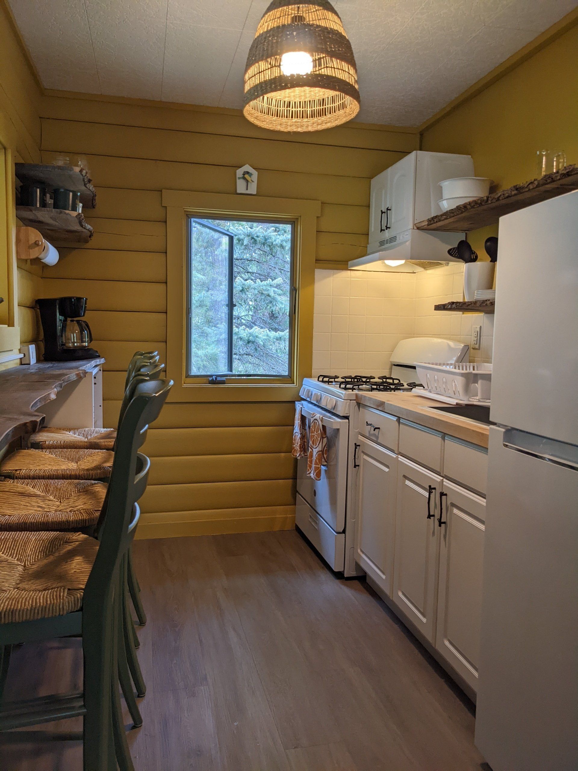 Cozy kitchenette of Cabin 4A at Belleayre Lodge, showing cabinets, stoves, refrigerator, and barstools at a counter.