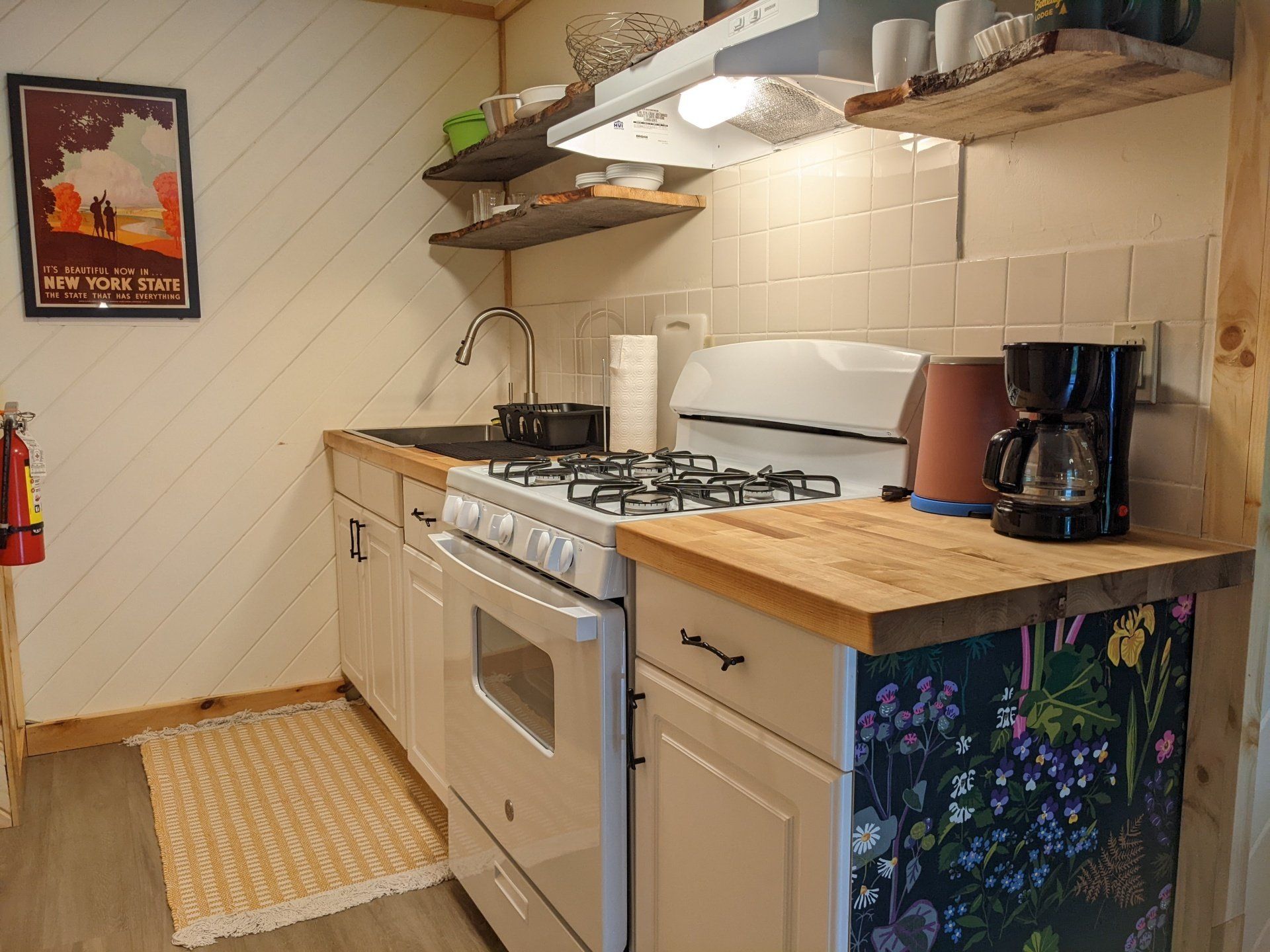 Kitchen of Cabin #4B at Belleayre Lodge in the Catskills, showing stove, sinks, stylish wall decor, and shelves.