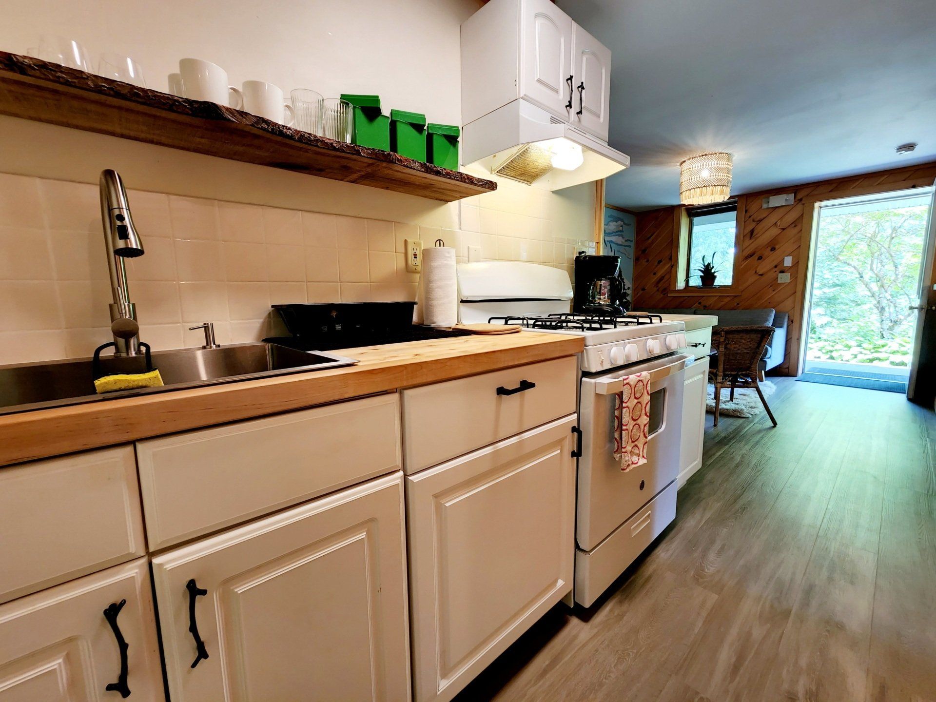 Kitchen of Cabin #5B at Belleayre Lodge, showing stove, sink, cabinets, and shelves.