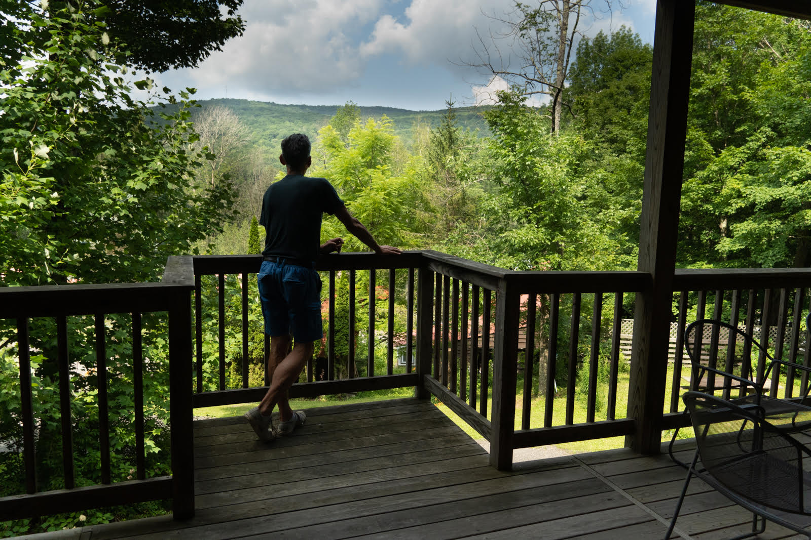 Man standing on porch of Cabin #6 at Belleayre Lodge, enjoying beautiful Catskills views.