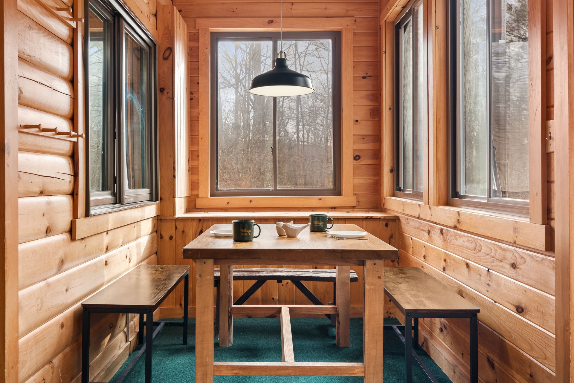 Cozy indoor dining for Cabin 6 in Belleayre Lodge in Pine Hill, NY. Wooden table and benches in front of beautiful view.