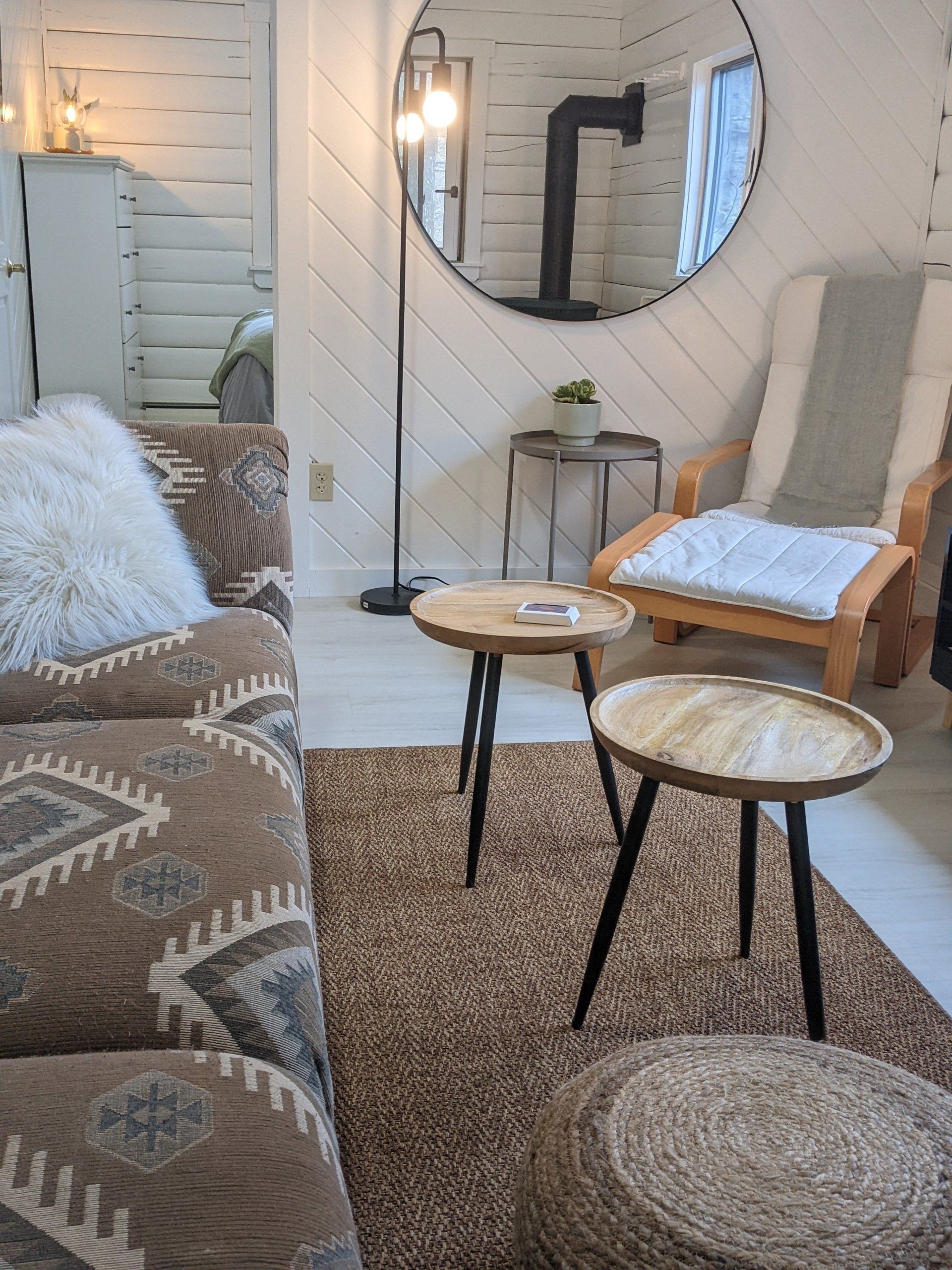 Interior of Cabin #6 at Belleayre Lodge, showing tables, a sofa, and a comfortable looking chair.