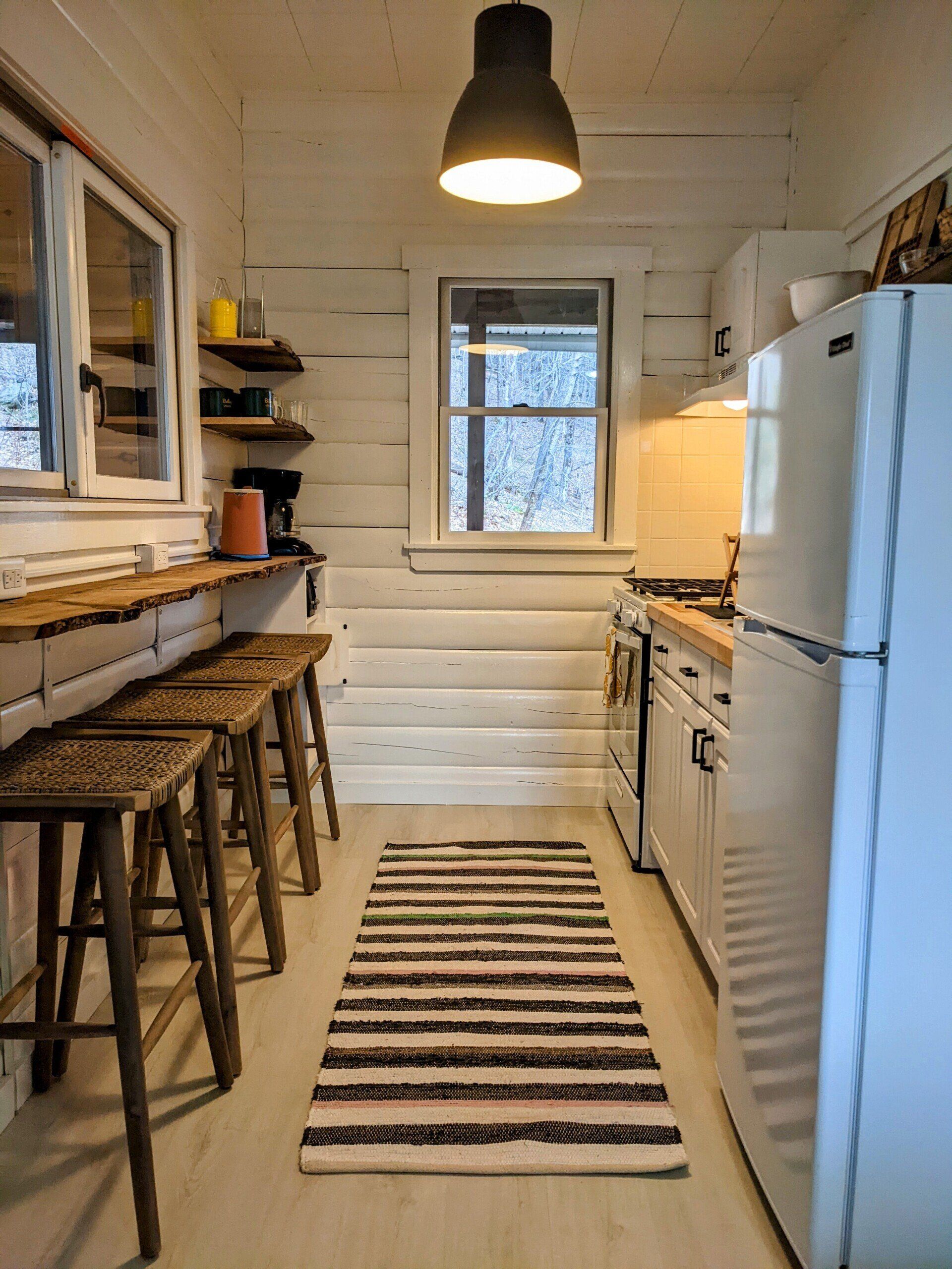 Kitchen of Cabin #6 at Belleayre Lodge in Upstate NY, with stools, stove, sink, and refrigerator.