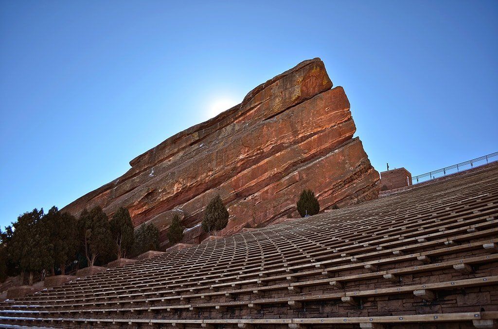 An empty amphitheater with a large rock in the background.