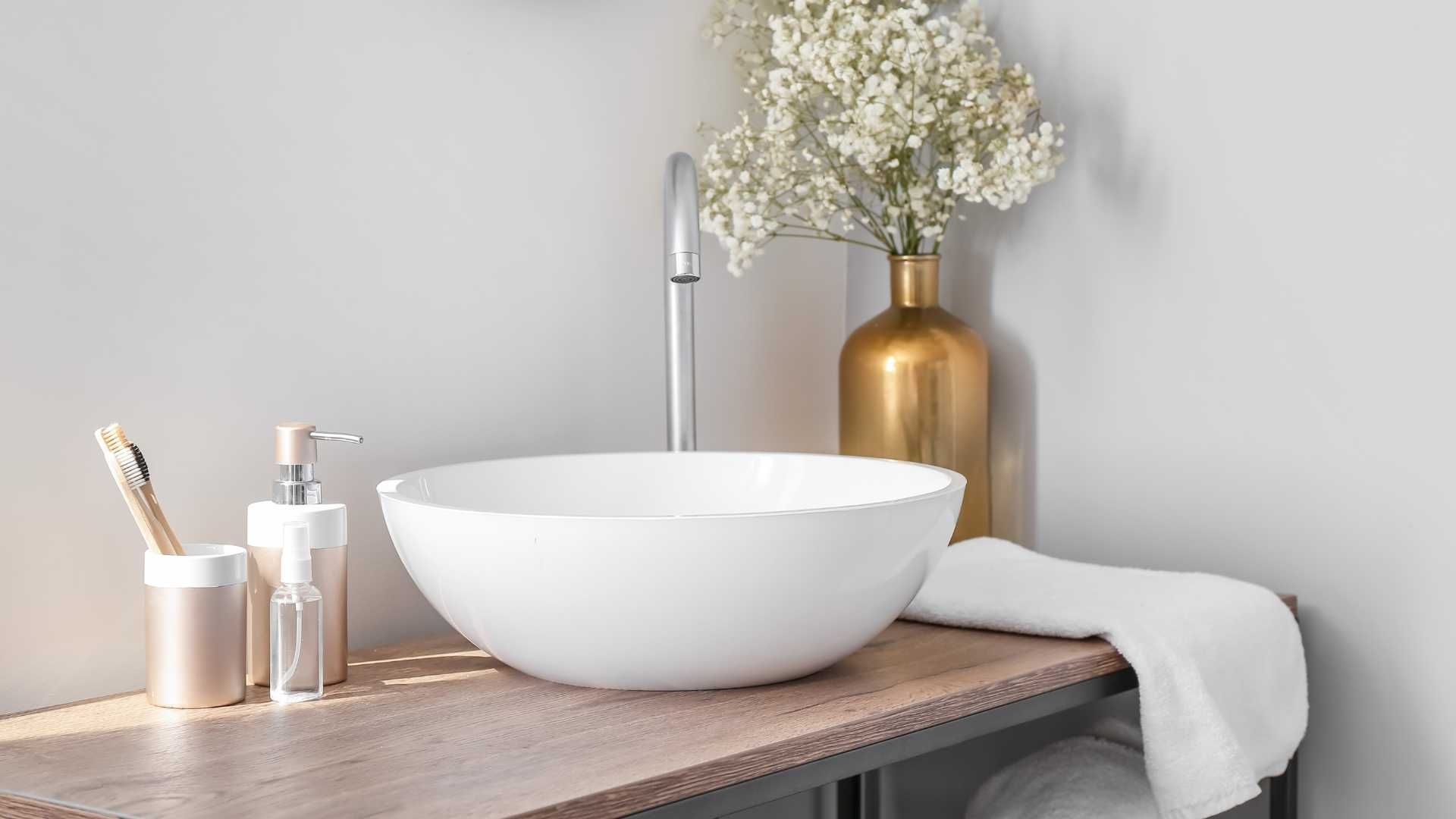 A bathroom with a sink and a vase of flowers on the counter.