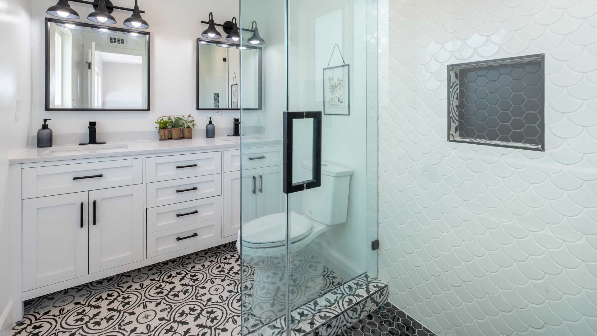 A bathroom with two sinks , a toilet , and a walk in shower.