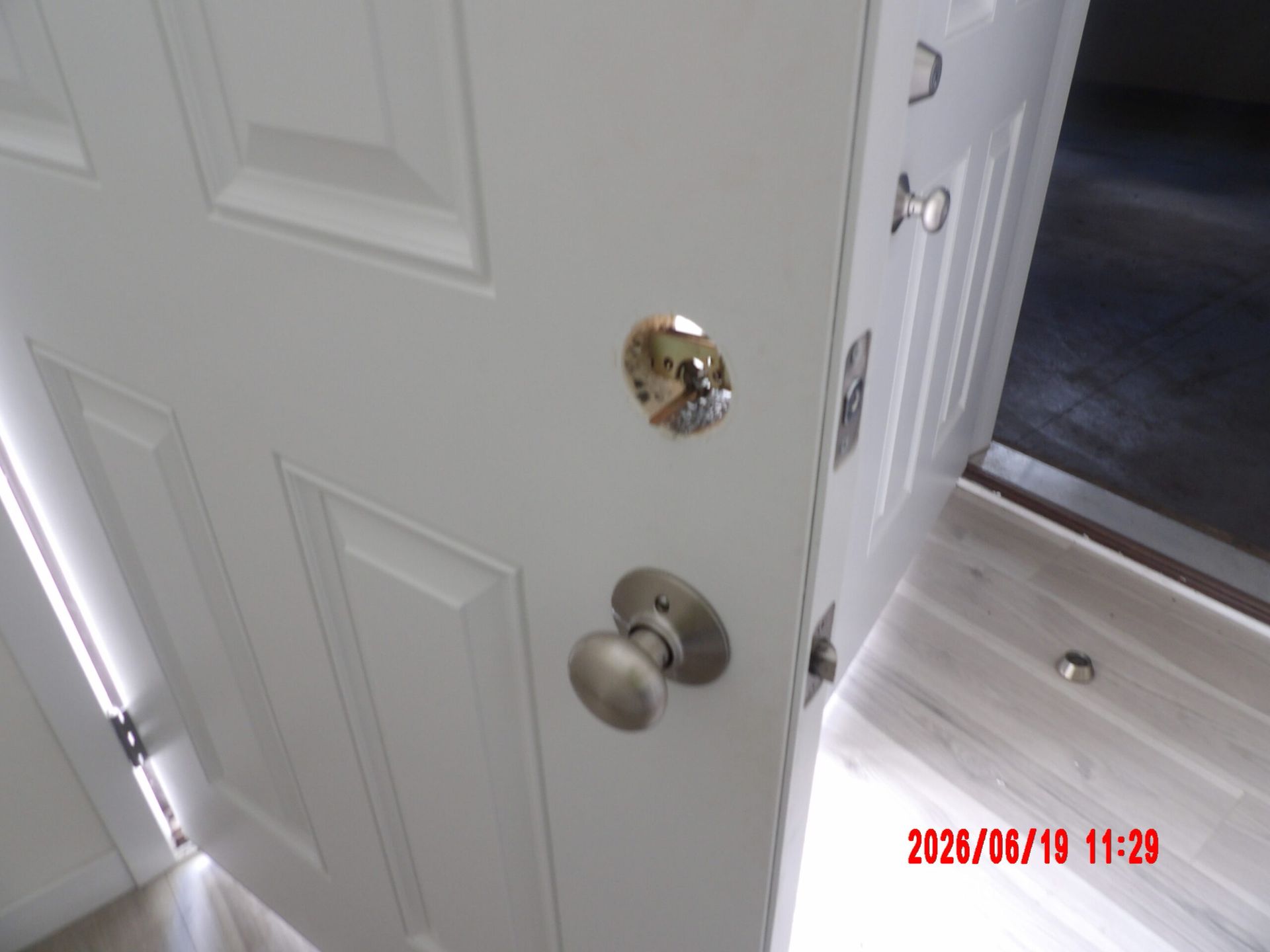 Partially open white front door with brass knob and deadbolt, leading into a home entryway
