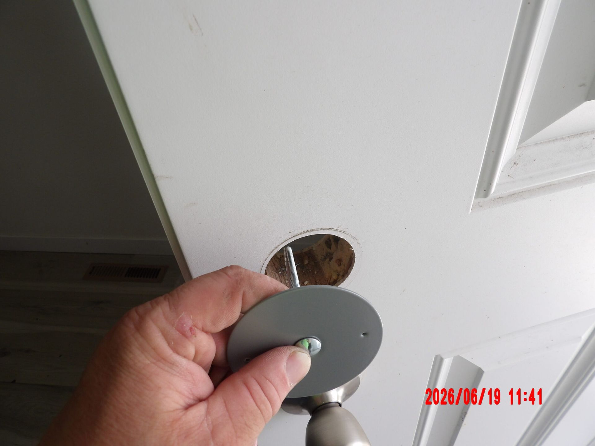 Hand holding a gray door knob near a white door with a missing lock hole