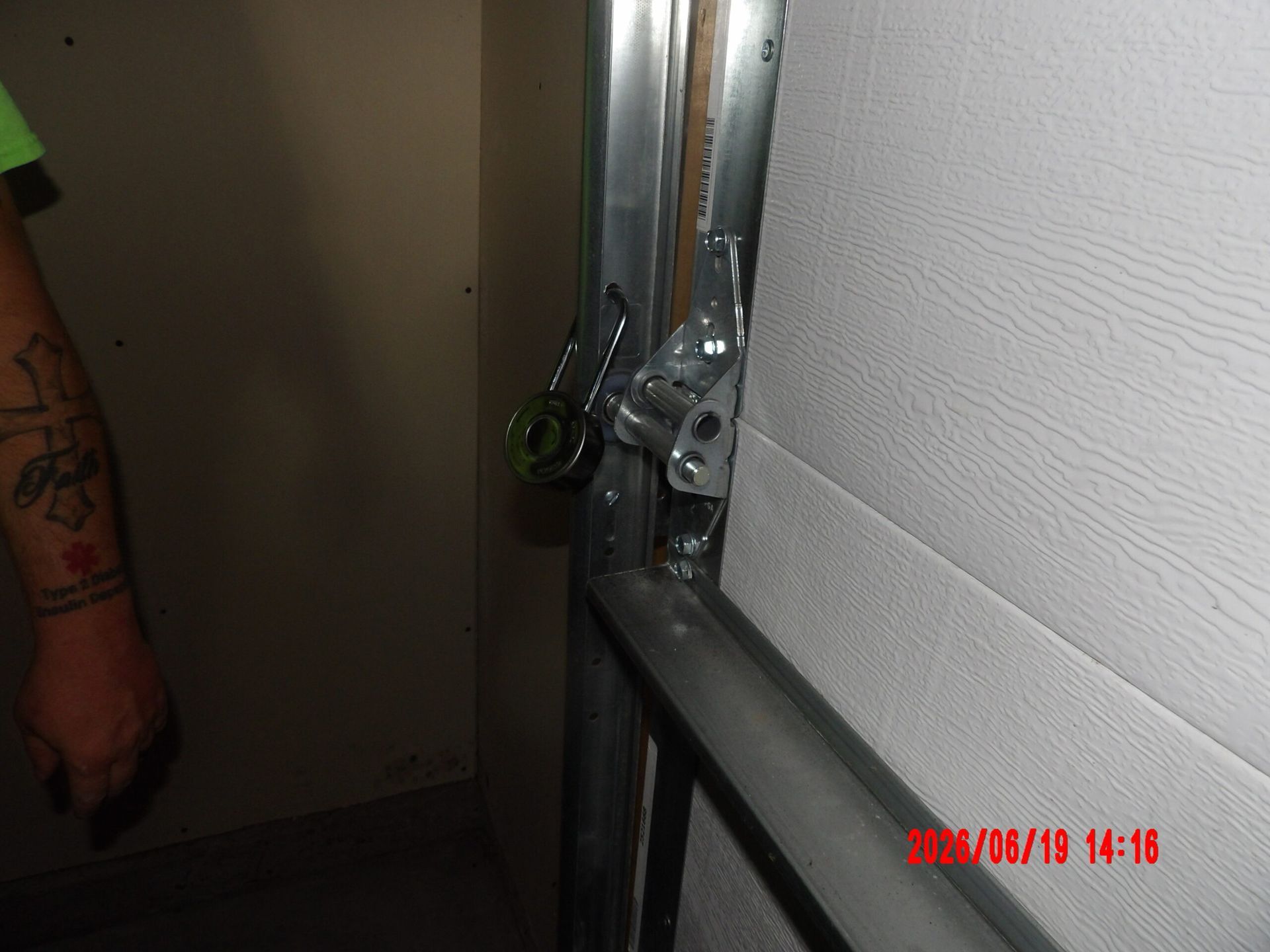Close-up of a metal door hinge and railing beside a beige wall.