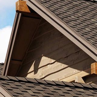 Close-up of a brown roof with dark gray shingles and wooden accents.