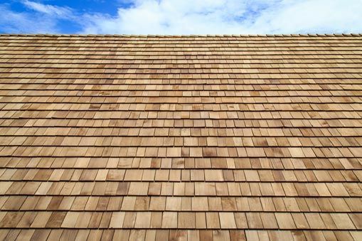Cedar shake roof against a blue sky with clouds.