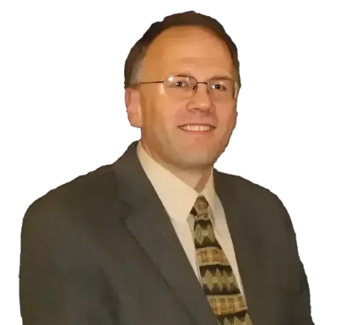 Portrait of a man in a dark suit, glasses, and patterned tie against a plain white background