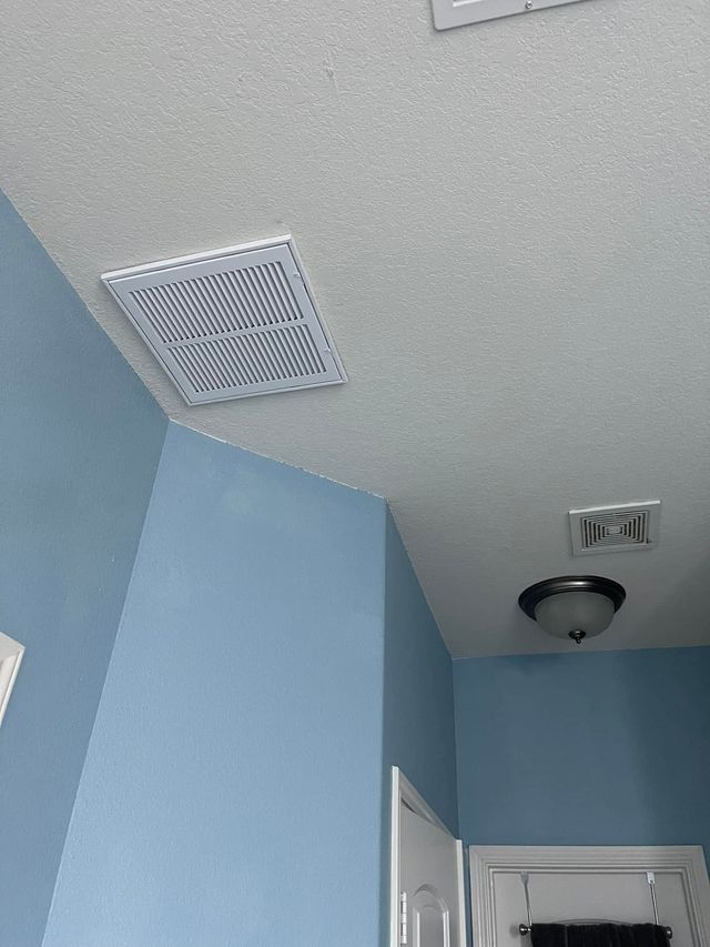 Ceiling corner with blue walls, white vents, and a dome light above a doorway