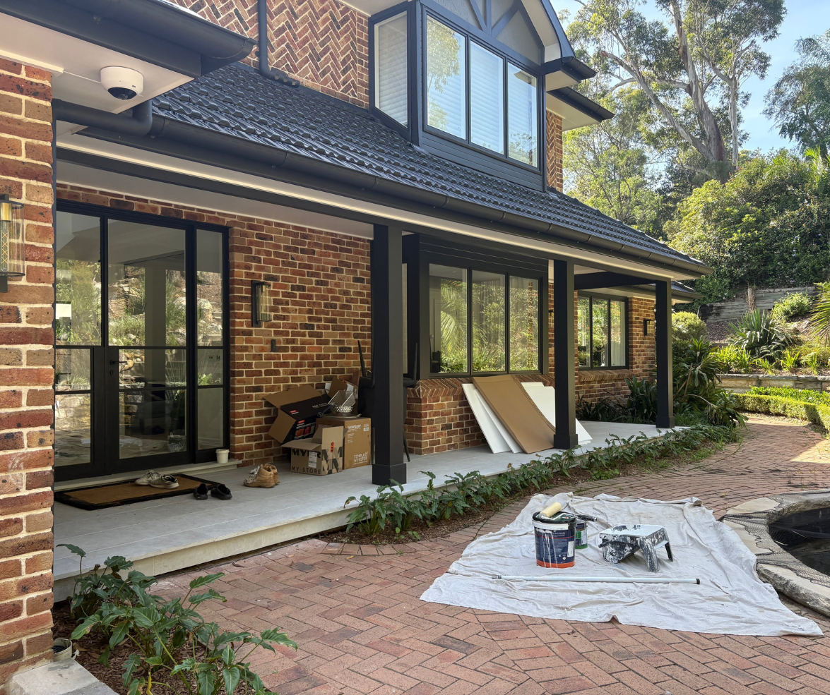 Brick house patio under construction with tools on a tarp beside a landscaped yard. Brick house patio under construction with tools on a tarp beside a landscaped yard.