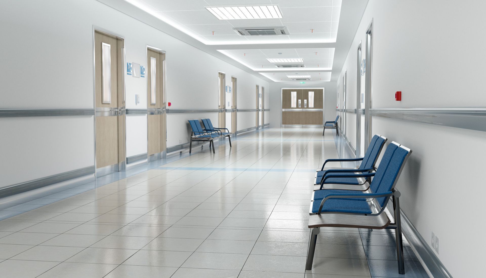 A bright, modern hospital hallway with blue chairs, white walls, and multiple closed doors.