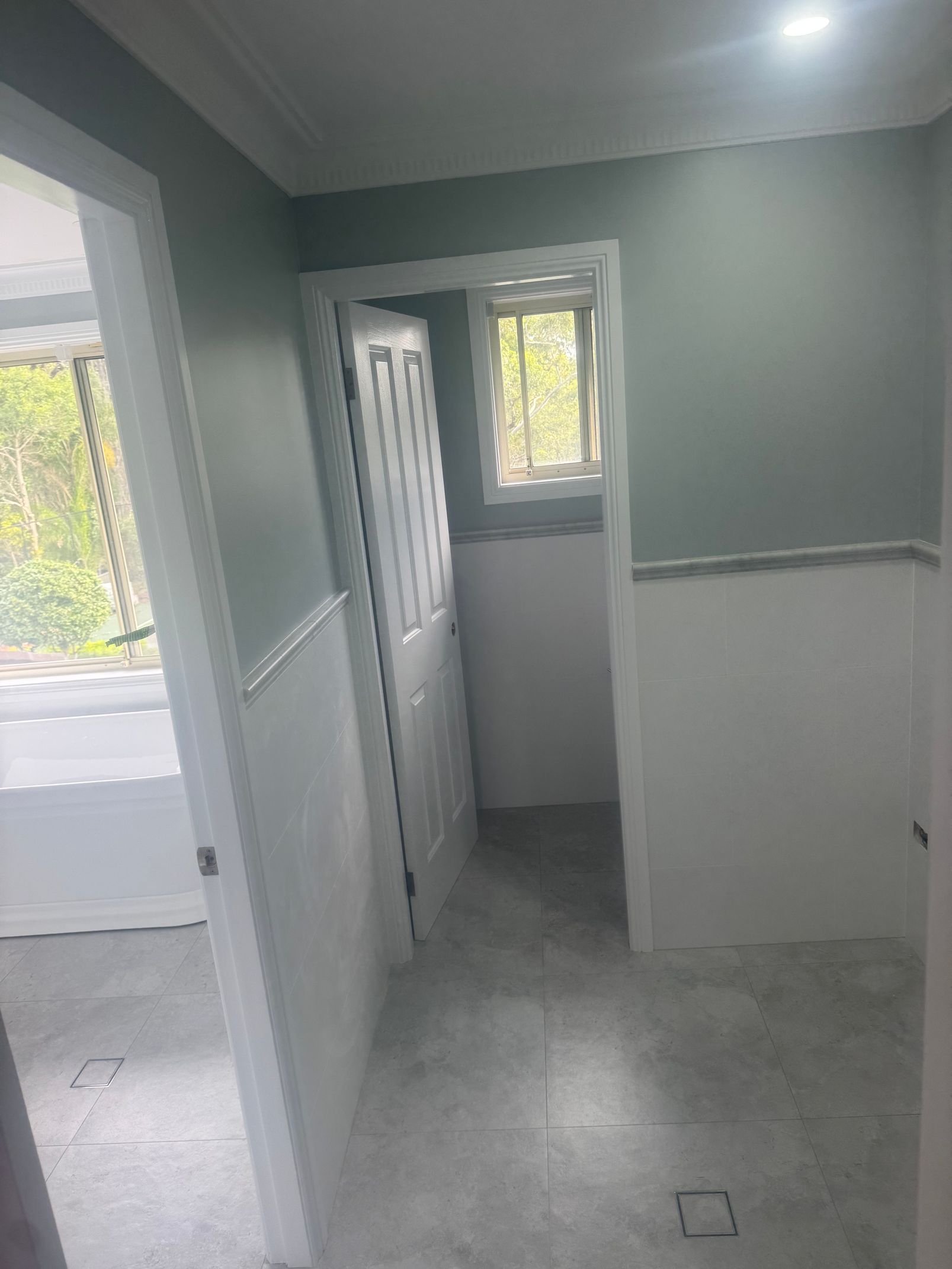 Small hallway with gray walls, white trim, and a window at the far end.