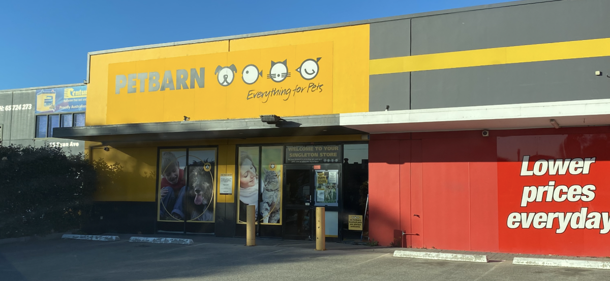 Exterior of a Petsbarn store with yellow signage, an entrance, and a red wall stating "Lower prices everyday."