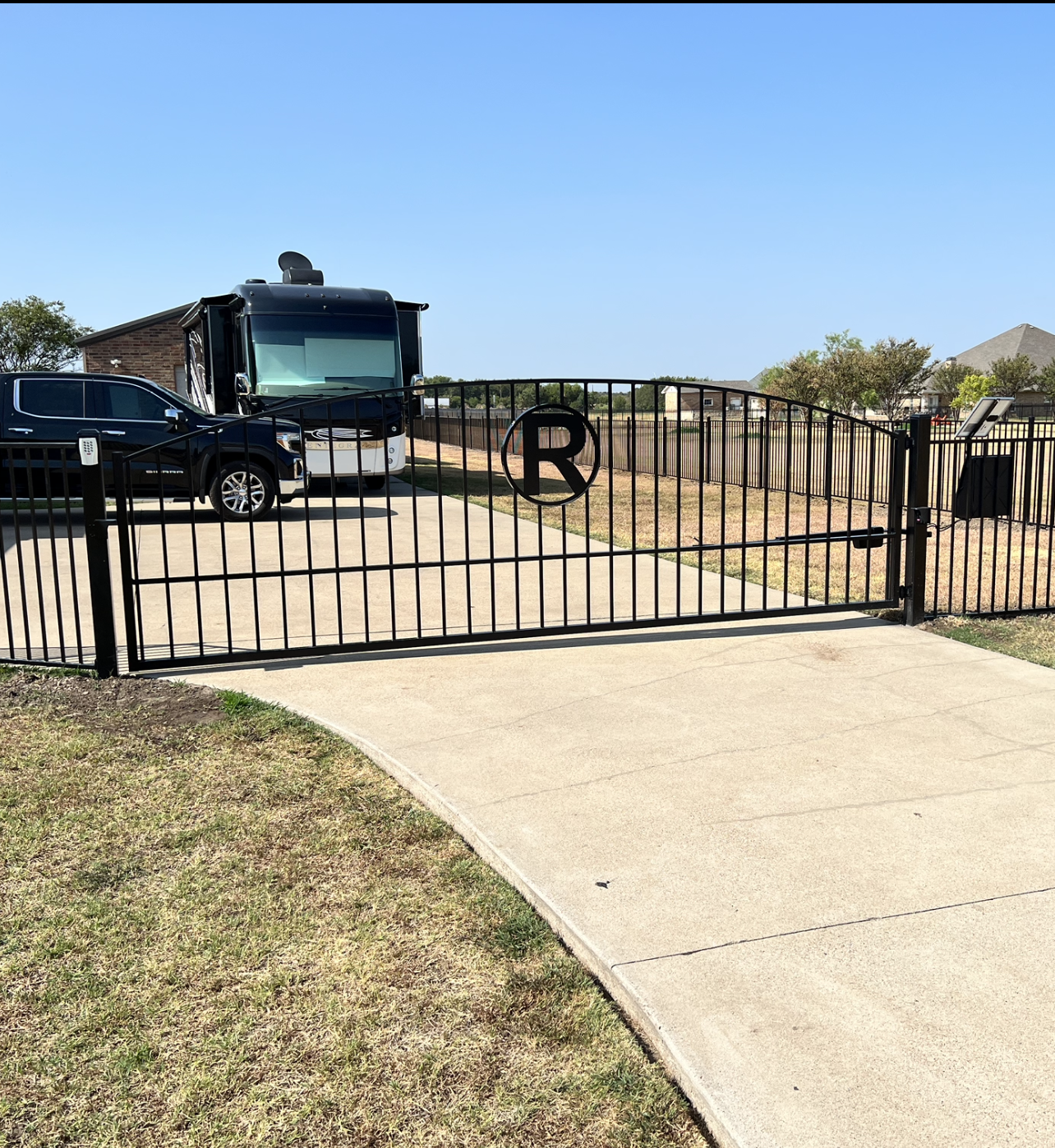 A rv is parked behind a gate with the letter r on it.