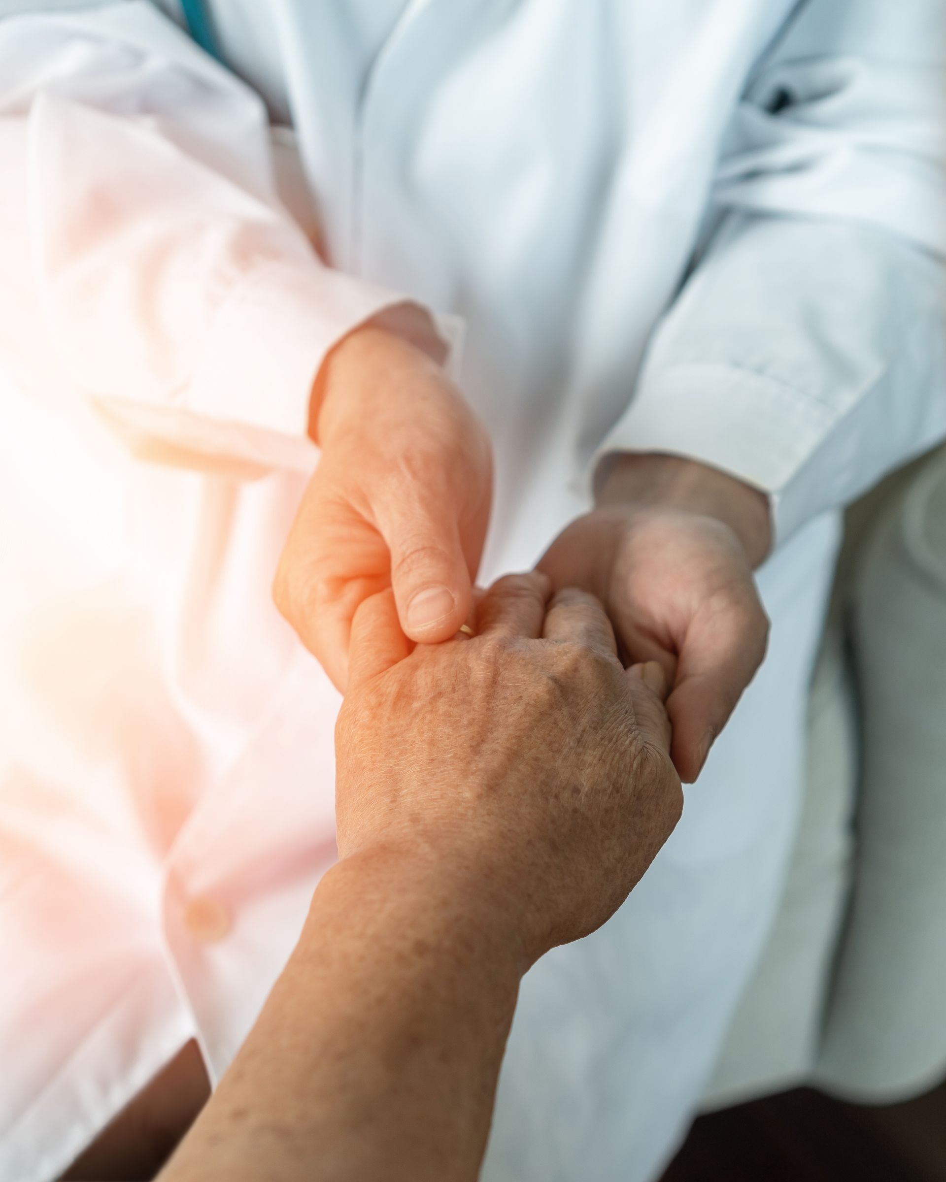 A close up of a doctor holding a patient 's hand.