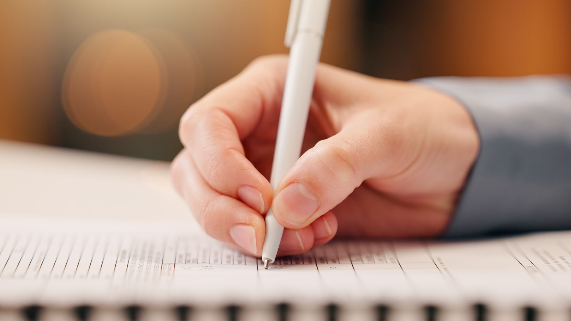 A person is writing on a piece of paper with a pen.
