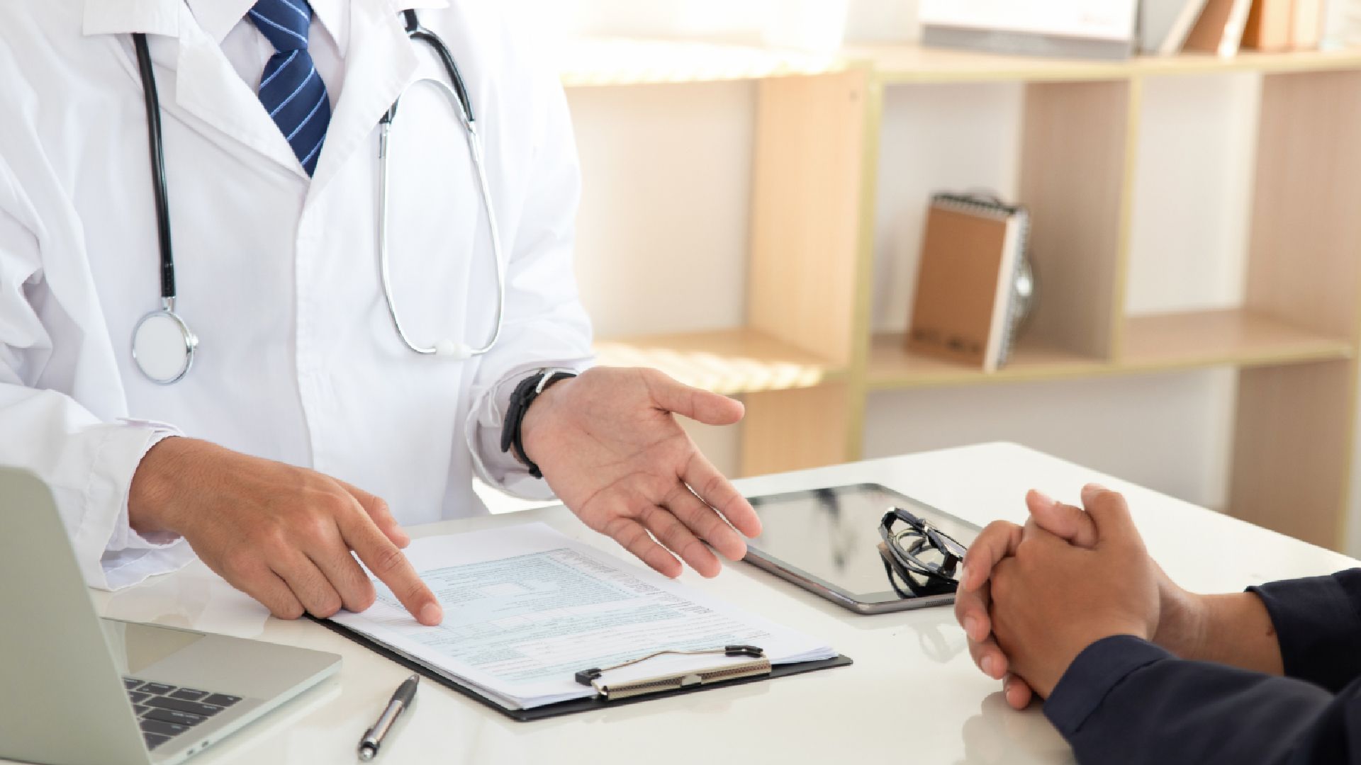 A doctor is talking to a patient while sitting at a desk.