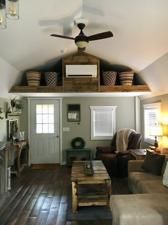 Cozy living room with vaulted ceiling, wood floors, ceiling fan, sofa, armchair, and rustic loft storage.