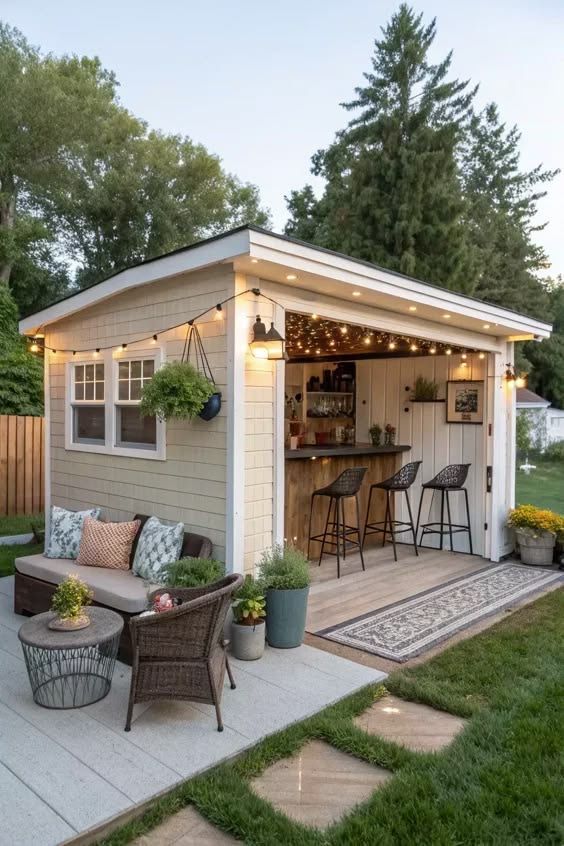 Cozy backyard shed with bar seating, string lights, and a small patio with wicker chairs and potted plants