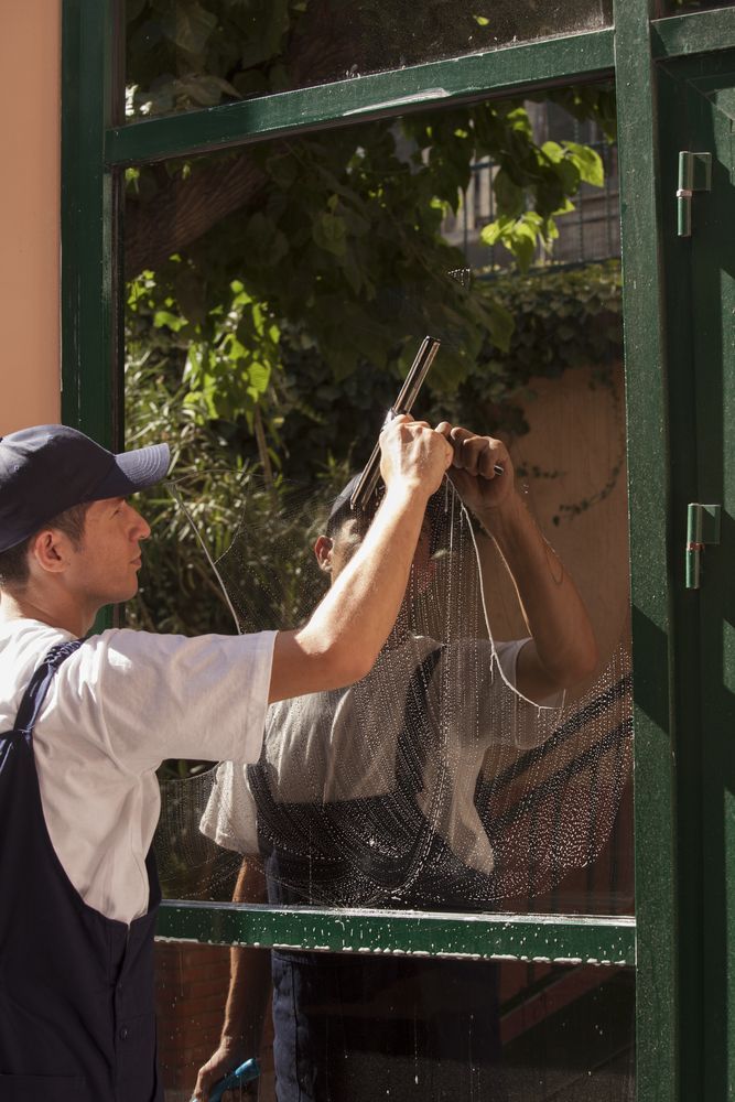 A Man is Cleaning a Window With a Brush — Dazzling Windows & Pressure Cleaning in Tugun, QLD