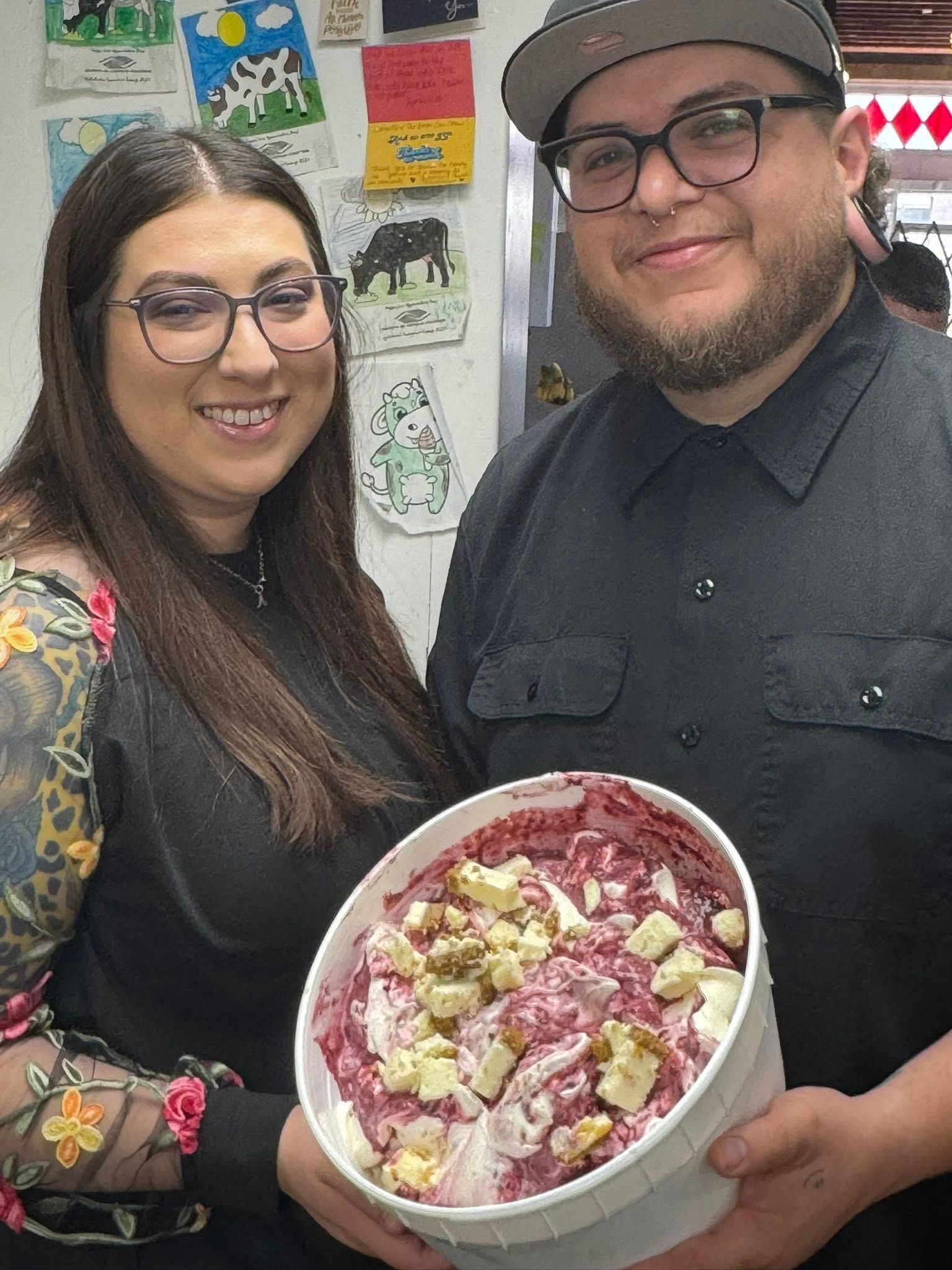 Two people holding a bowl of colorful salad, smiling indoors
