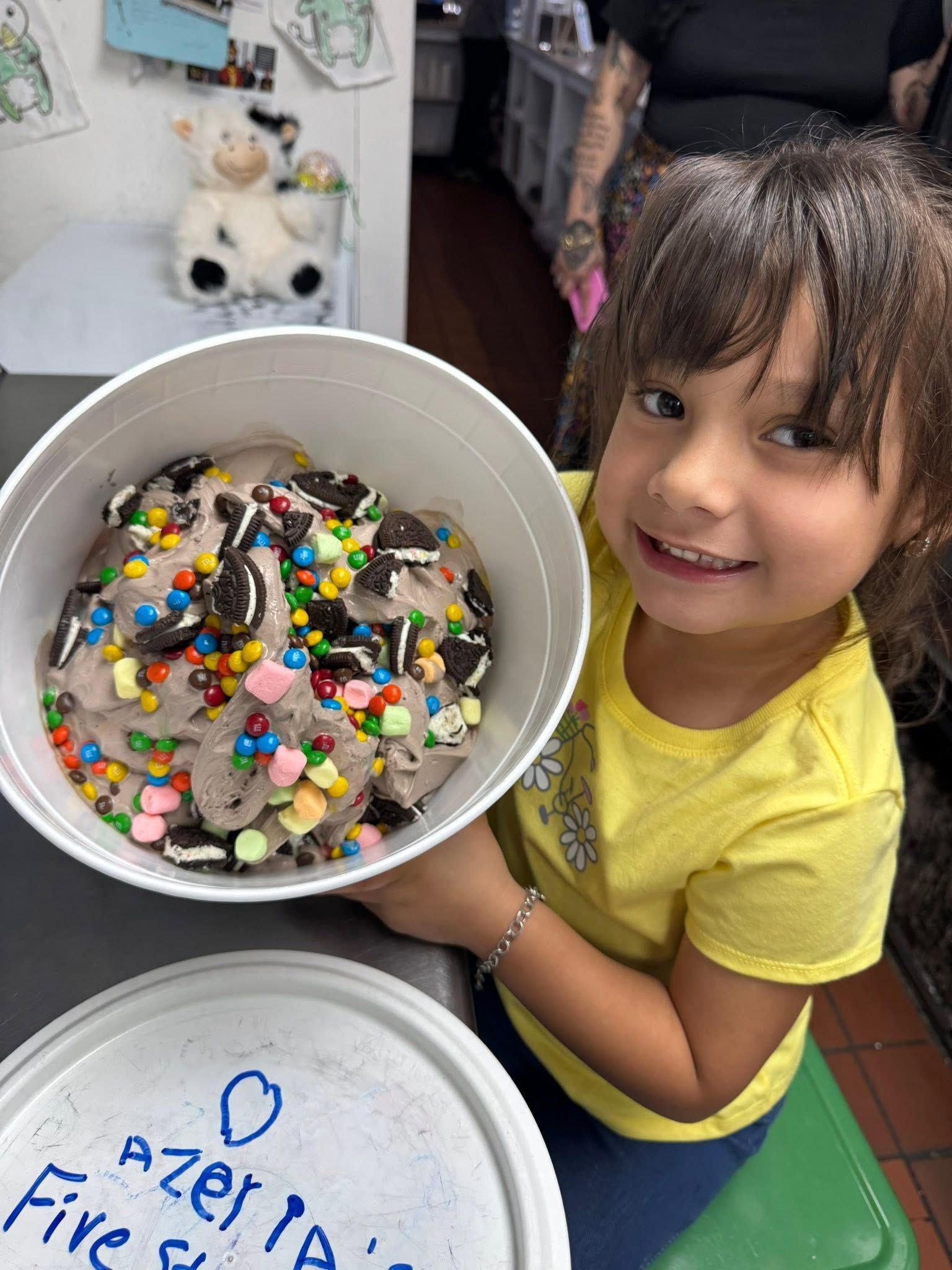 Girl smiling and holding a bowl of decorated cookies in a kitchen